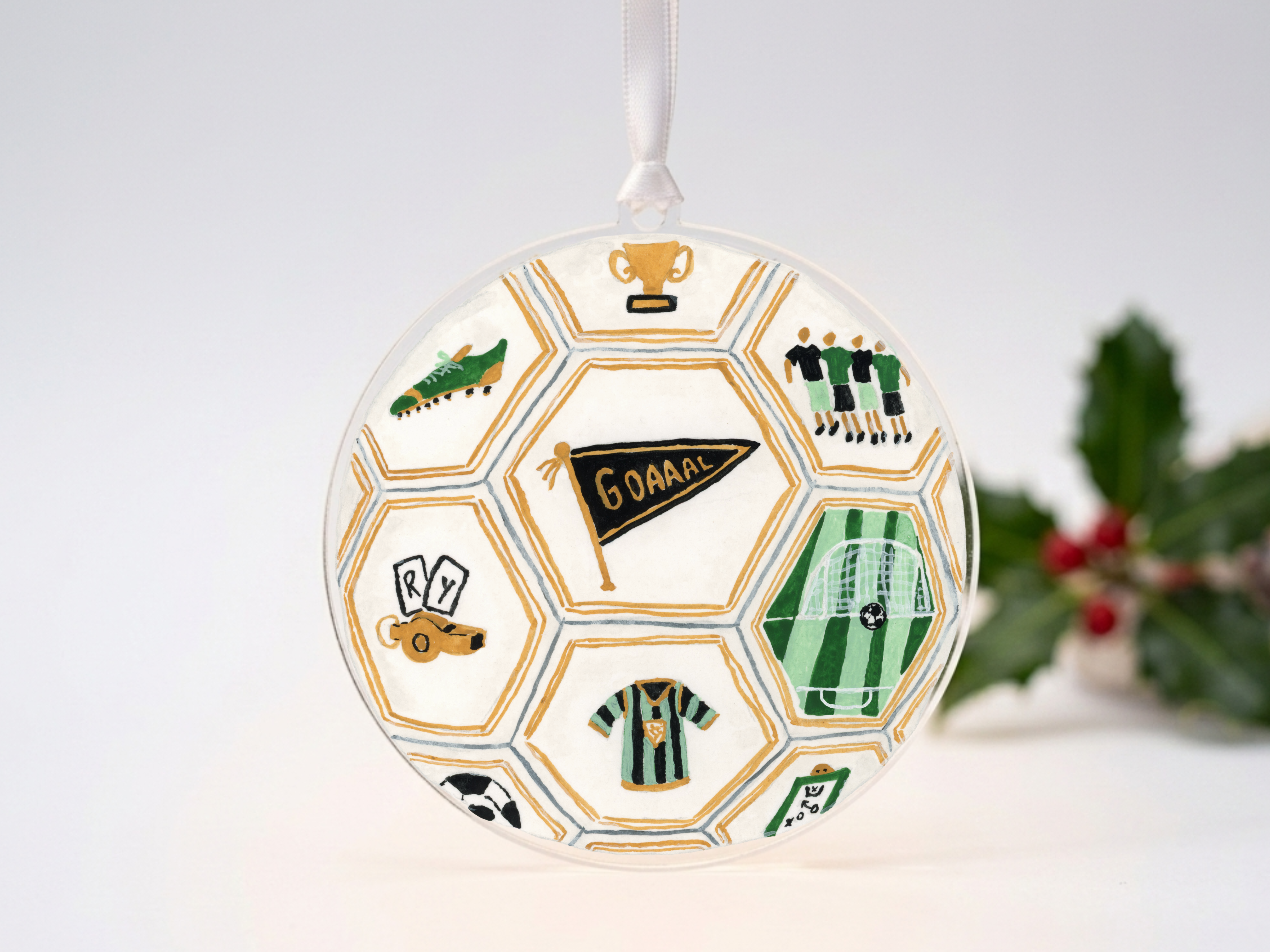 A round ornament with a soccer ball design, featuring various soccer-related elements such as a trophy, a soccer ball, and a soccer jersey.