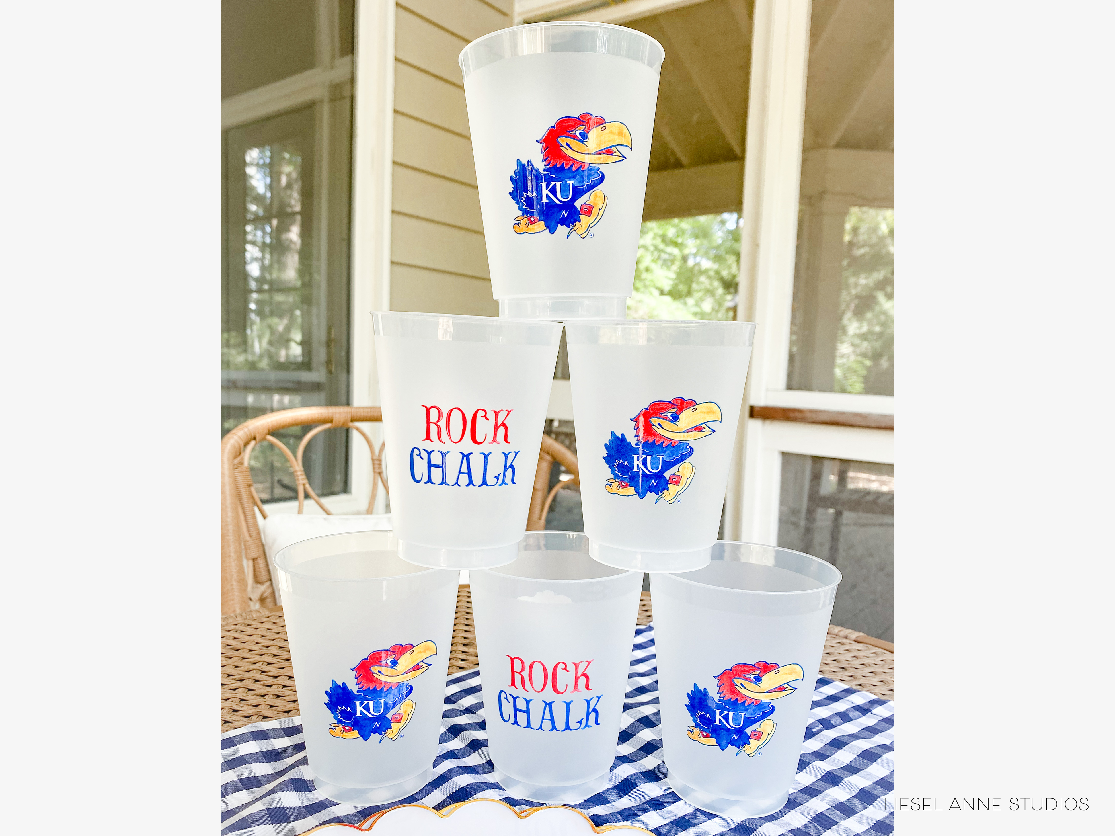 A stack of six clear plastic cups with the text "ROCK CHALLE" printed on them, featuring the mascot of Kansas University.