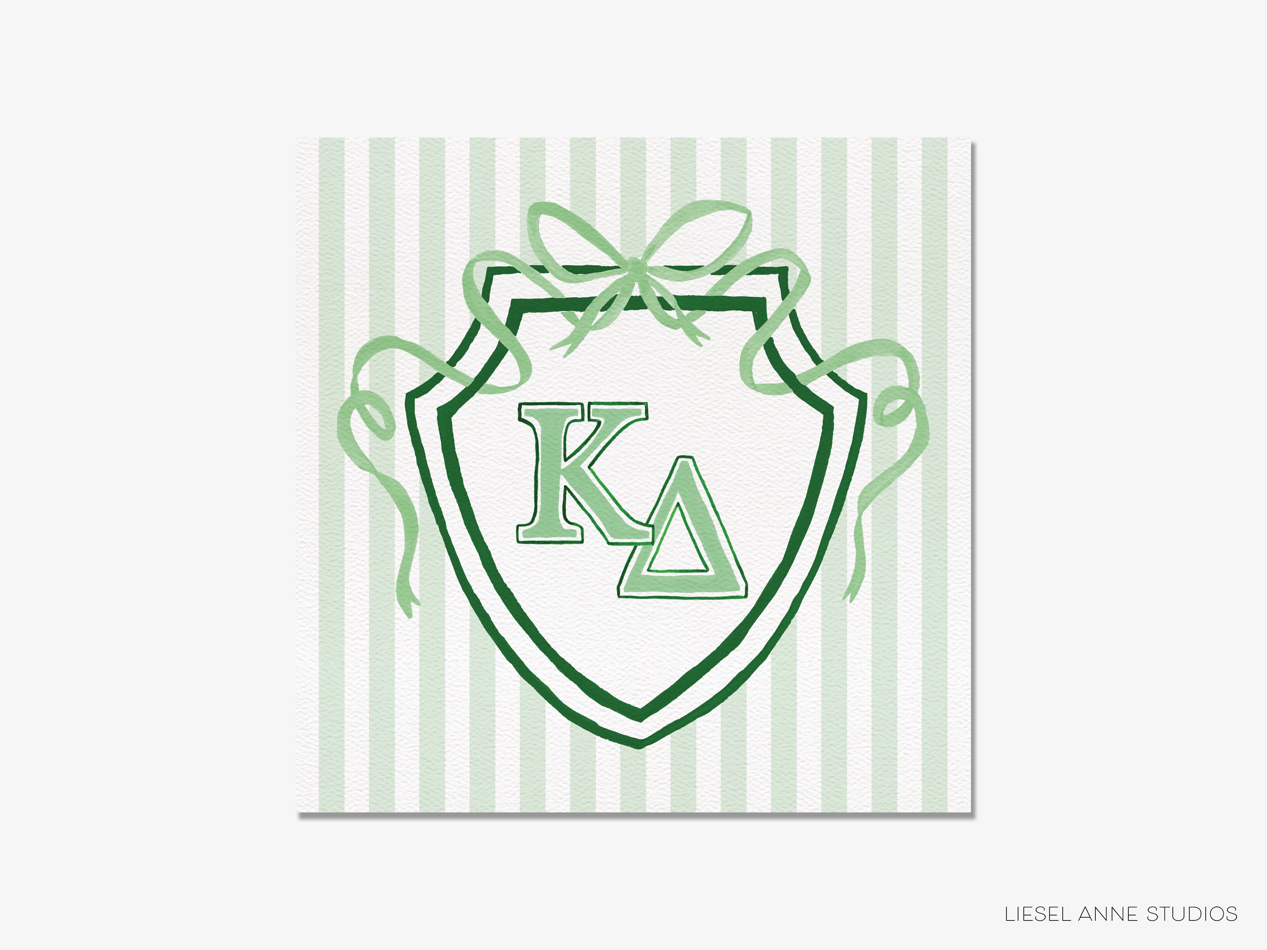 a shield-shaped emblem with the letters 'K' and 'Δ' prominently displayed in the center. The shield is surrounded by green ribbons, creating a decorative and visually appealing design.