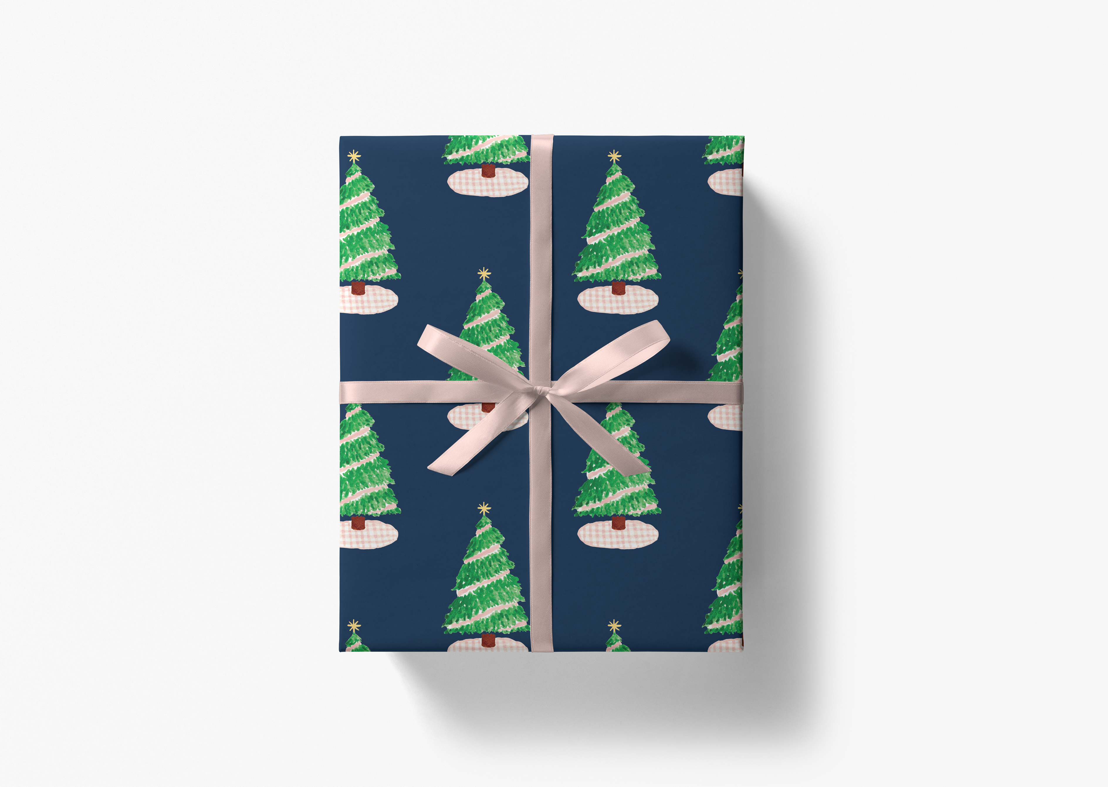 A gift box with a pattern of green Christmas trees on a dark blue background, tied with a pink ribbon.