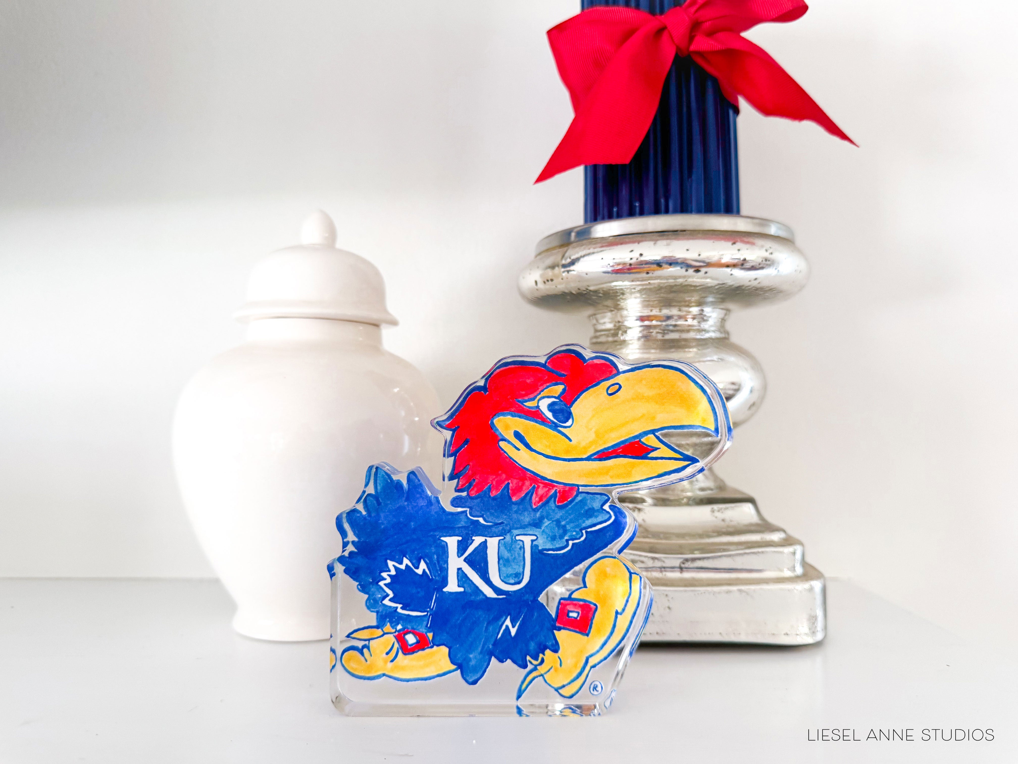 a blue vase with a red bow next to a white vase with a kansas state