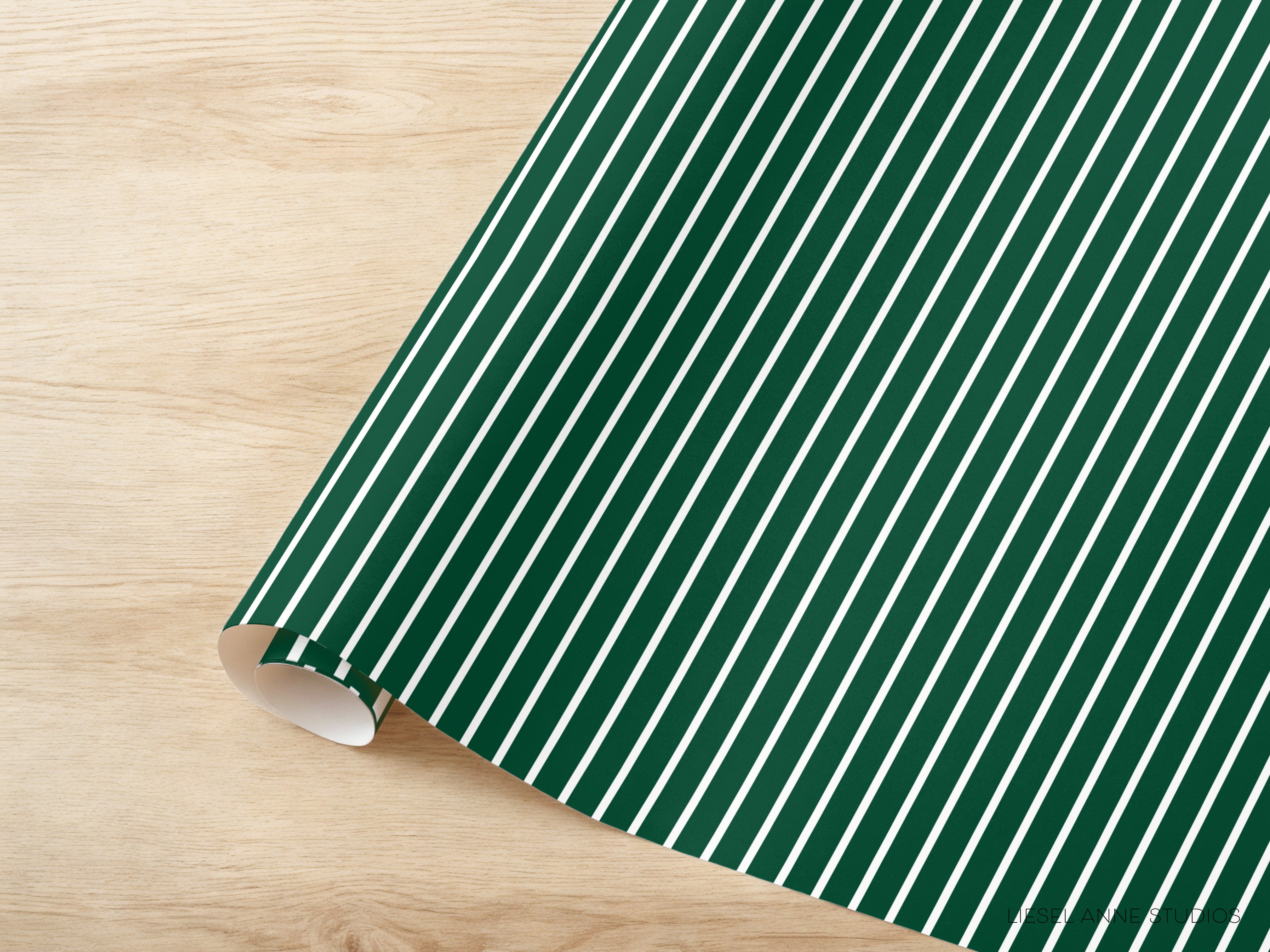 A roll of green and white striped wrapping paper is placed on a wooden surface.