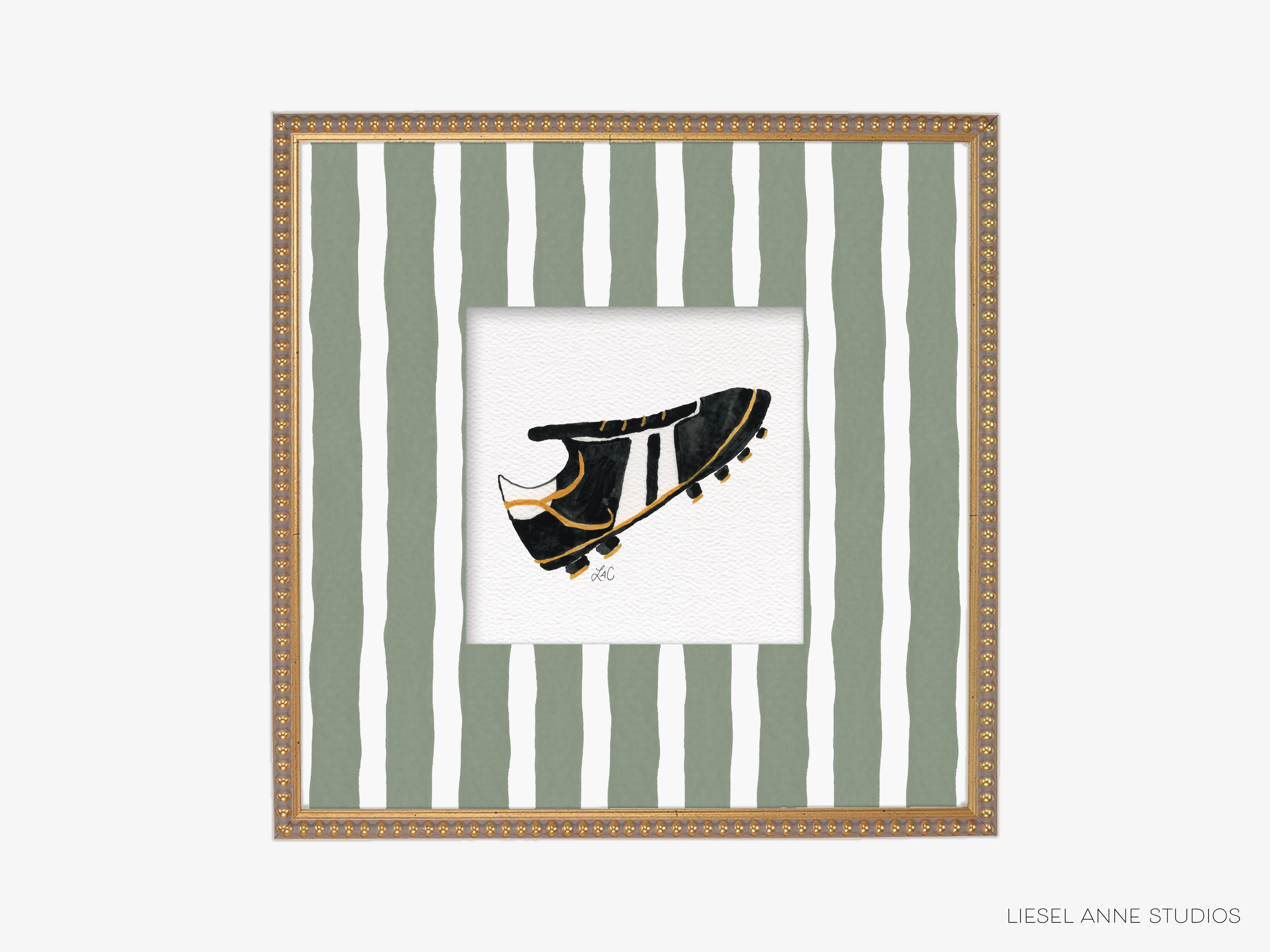 A framed image of a black and gold soccer cleat against a background of green and white striped vertical lines.