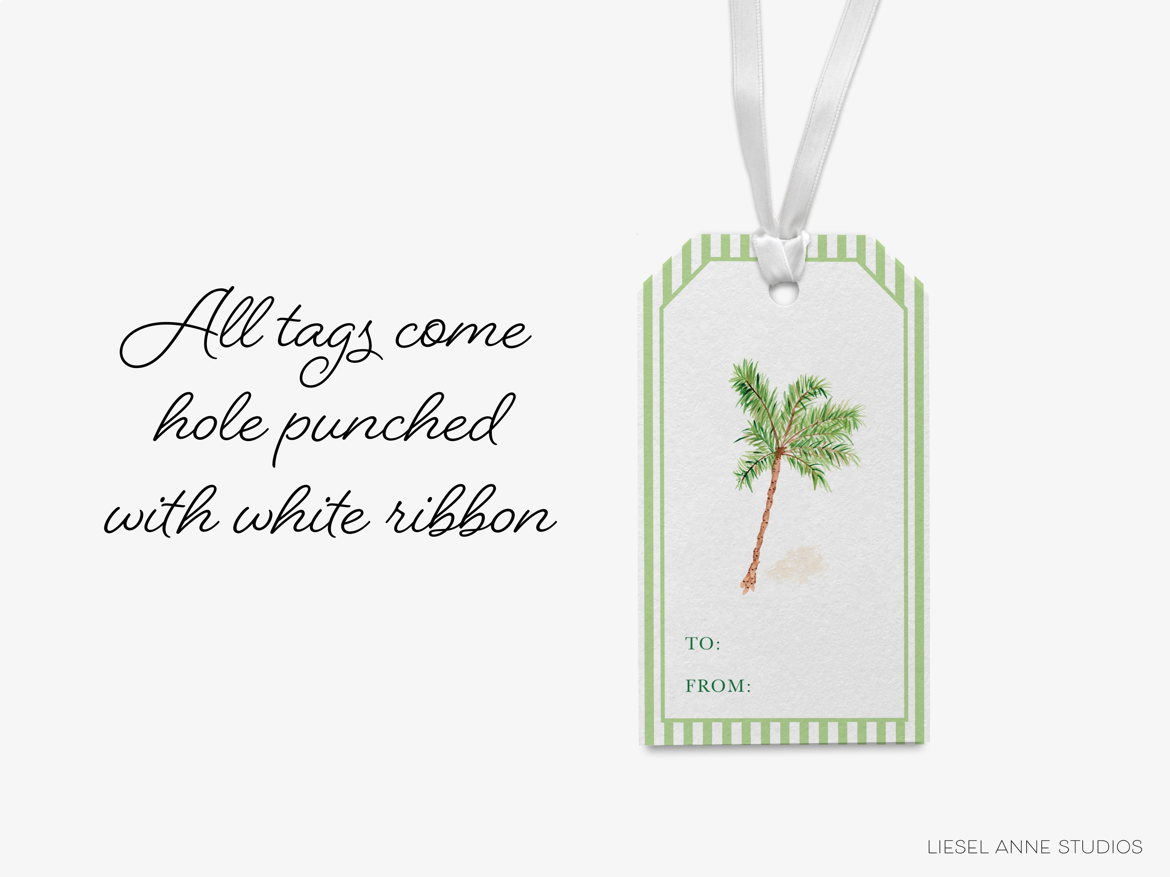 A white ribbon tag with a palm tree illustration and text that reads "All tags come hole punched with white ribbon" and "TO: FROM:"