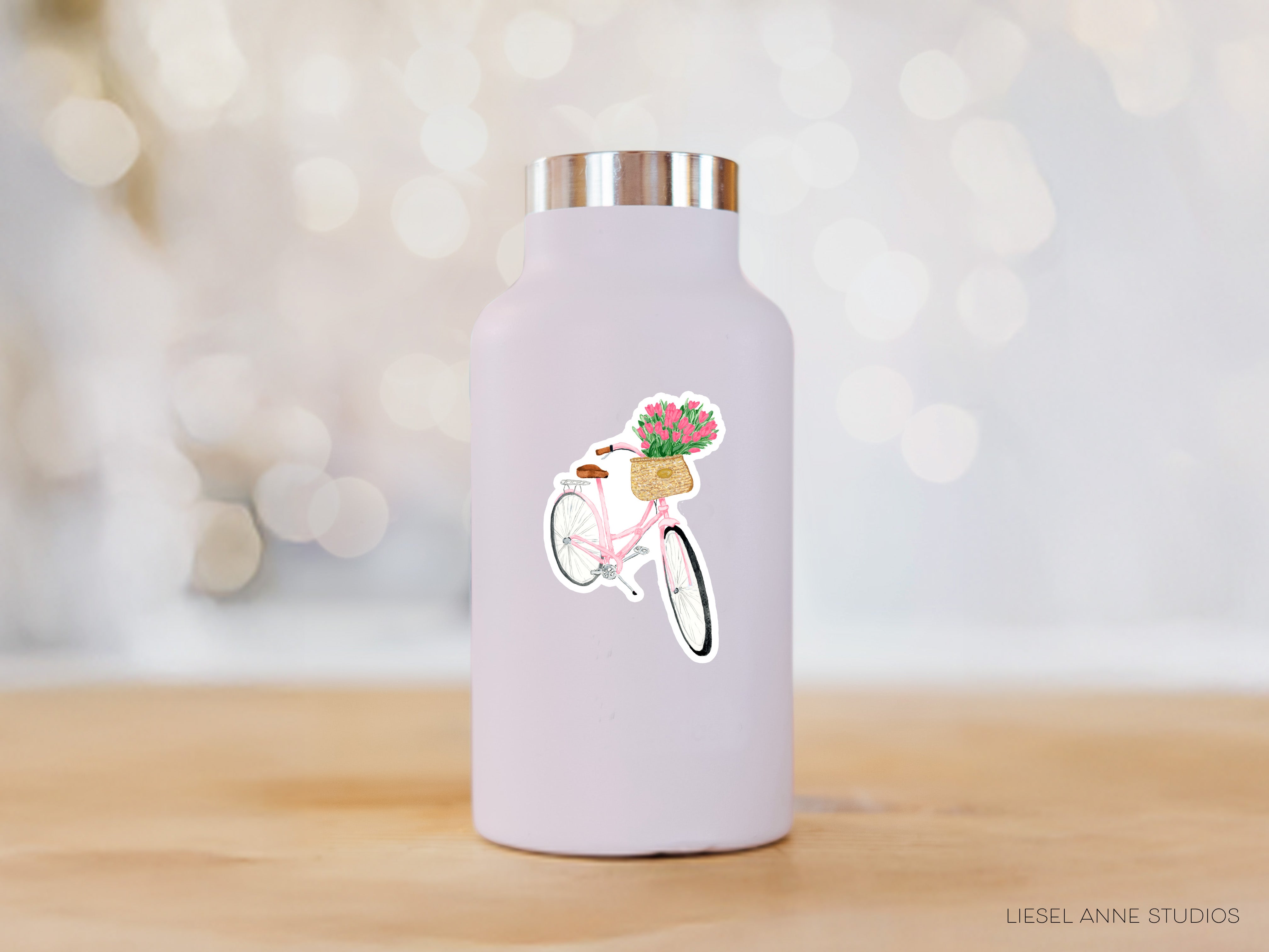 A white water bottle with a sticker of a bicycle and flowers on it, placed on a wooden surface.