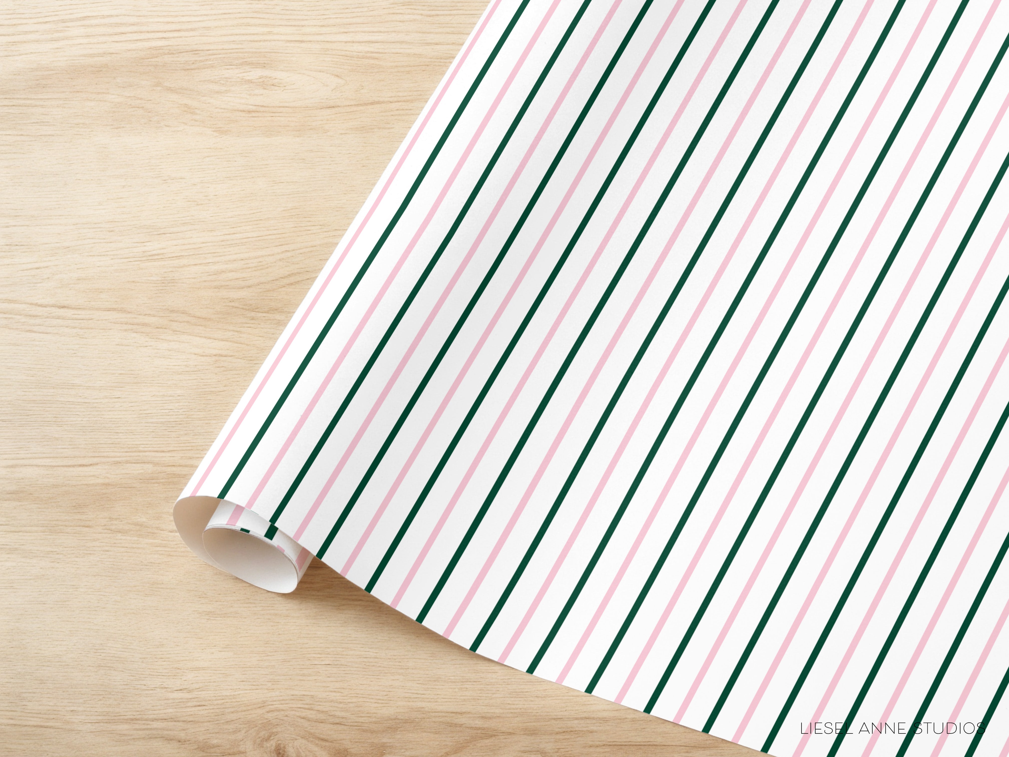 A roll of wrapping paper with a striped pattern in shades of pink and green is placed on a wooden surface.