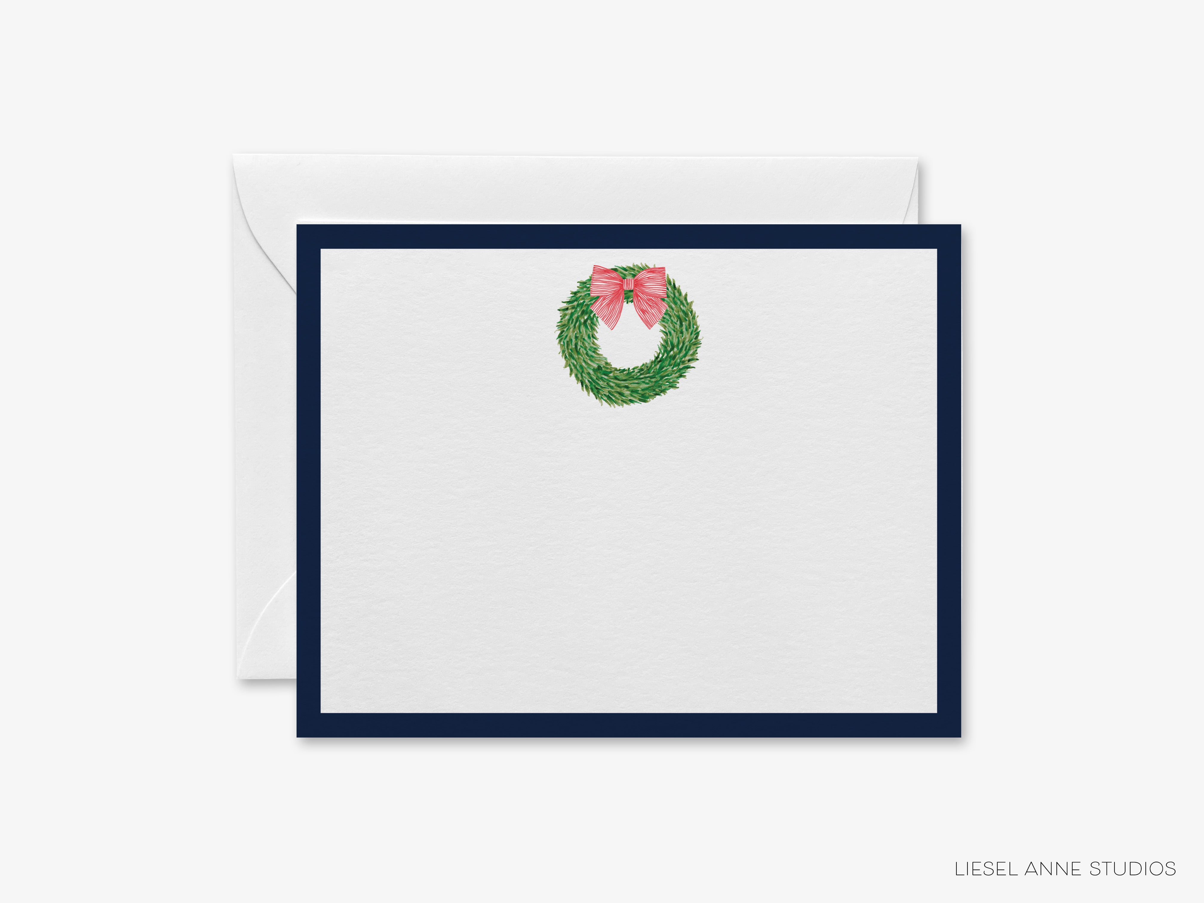 A white card with a navy blue border and a wreath with a pink bow on it.