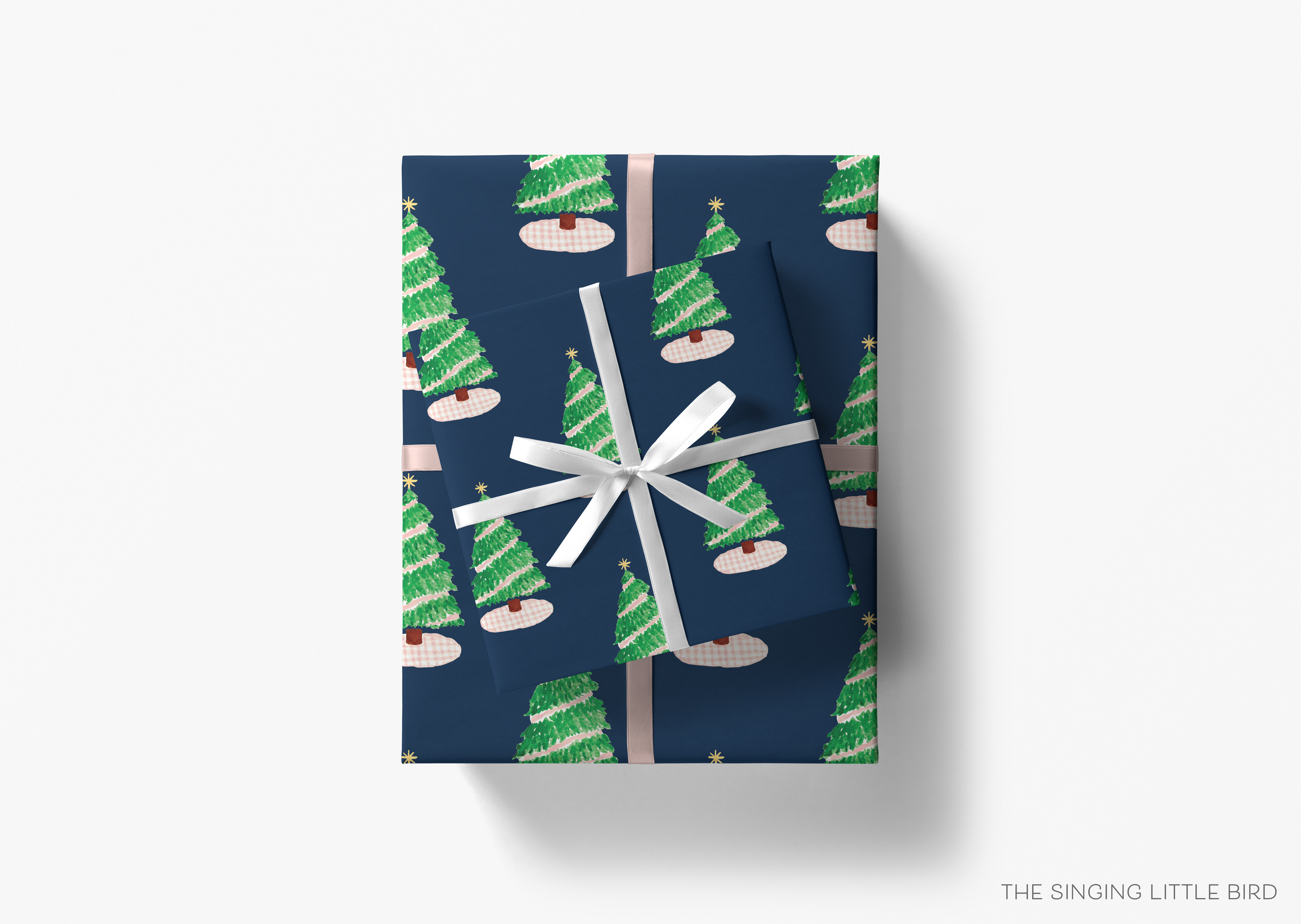 A gift box with a pattern of green Christmas trees and a white ribbon tied around it.