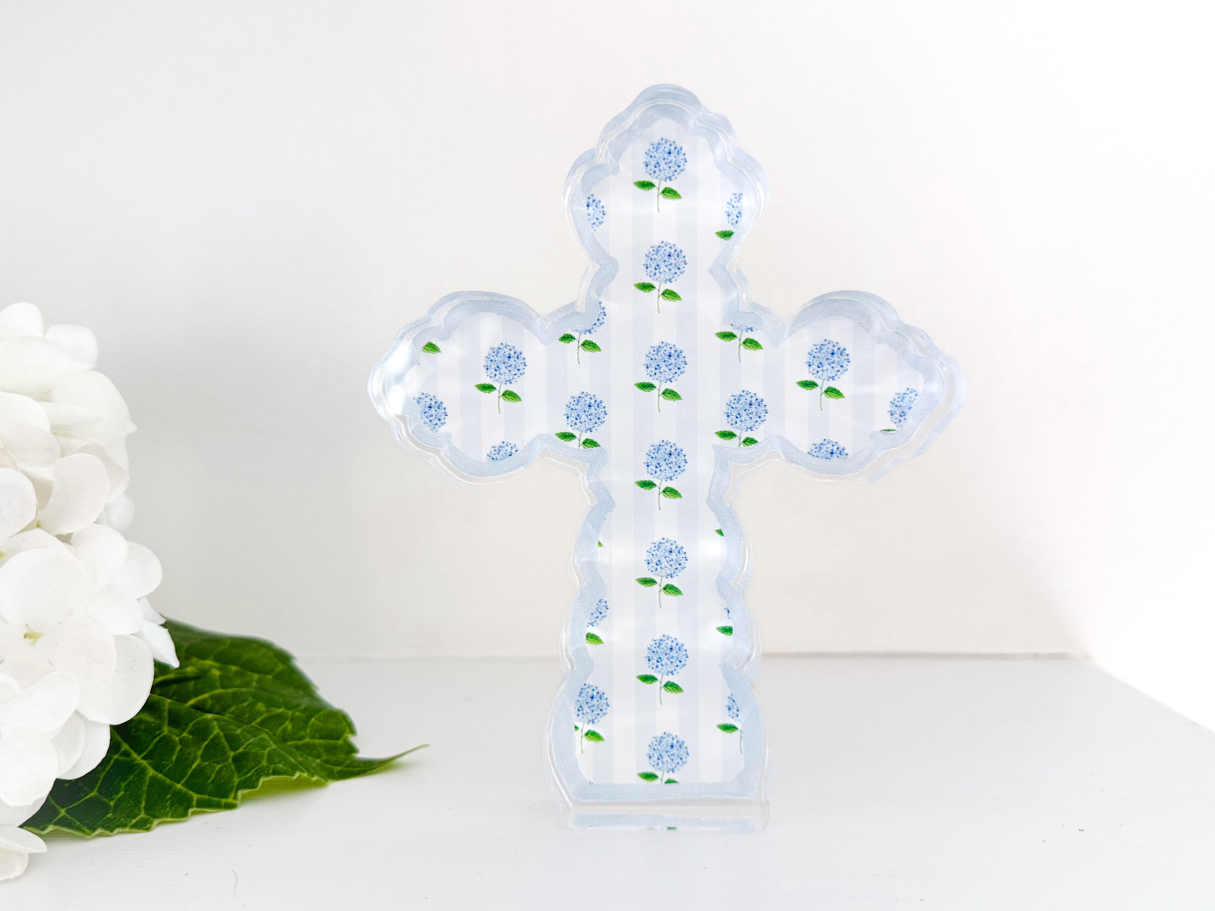 a glass cross sitting next to a white flower
