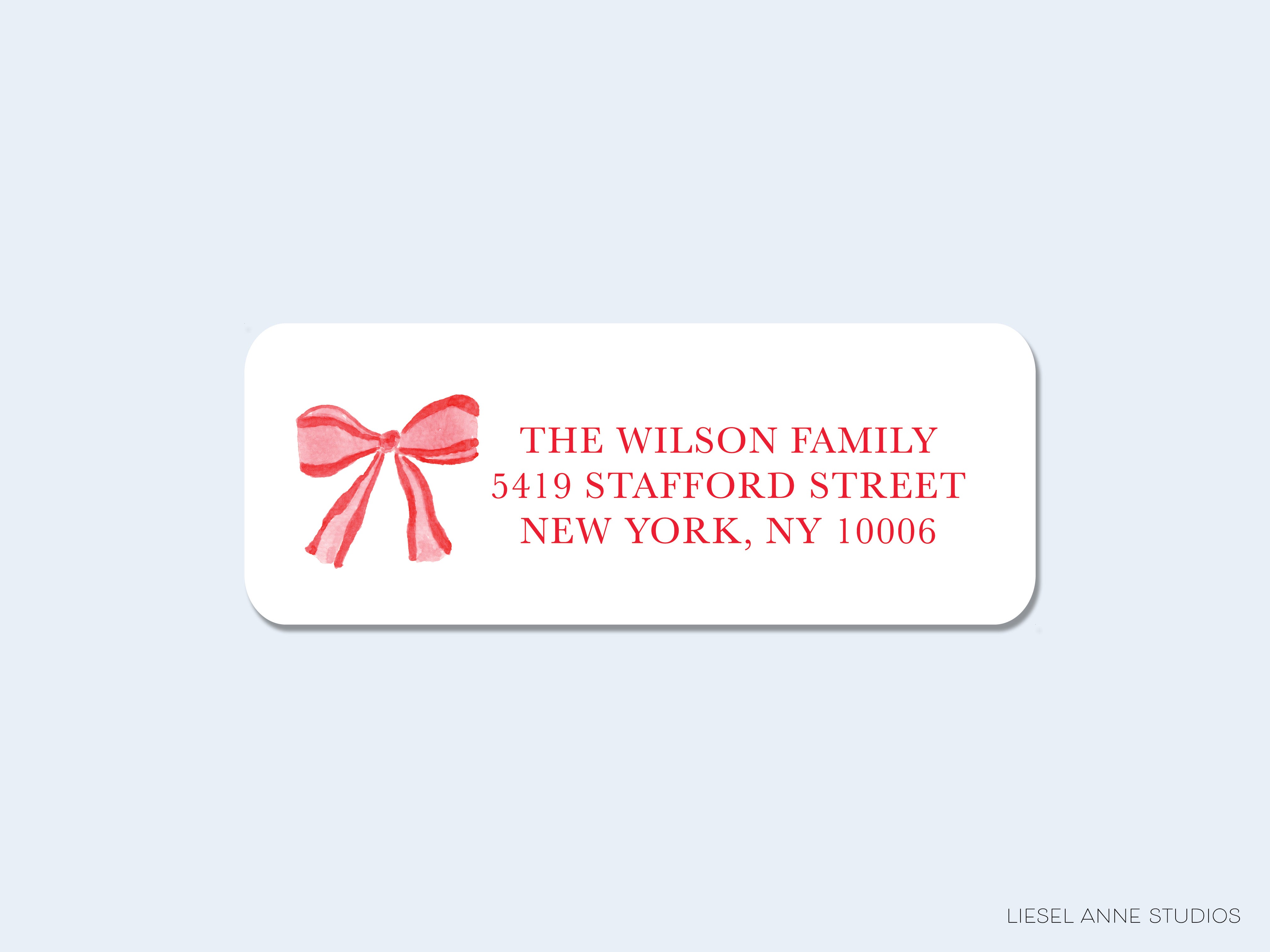 The image is a white rectangular label with a red bow on it, displaying the address of a family.