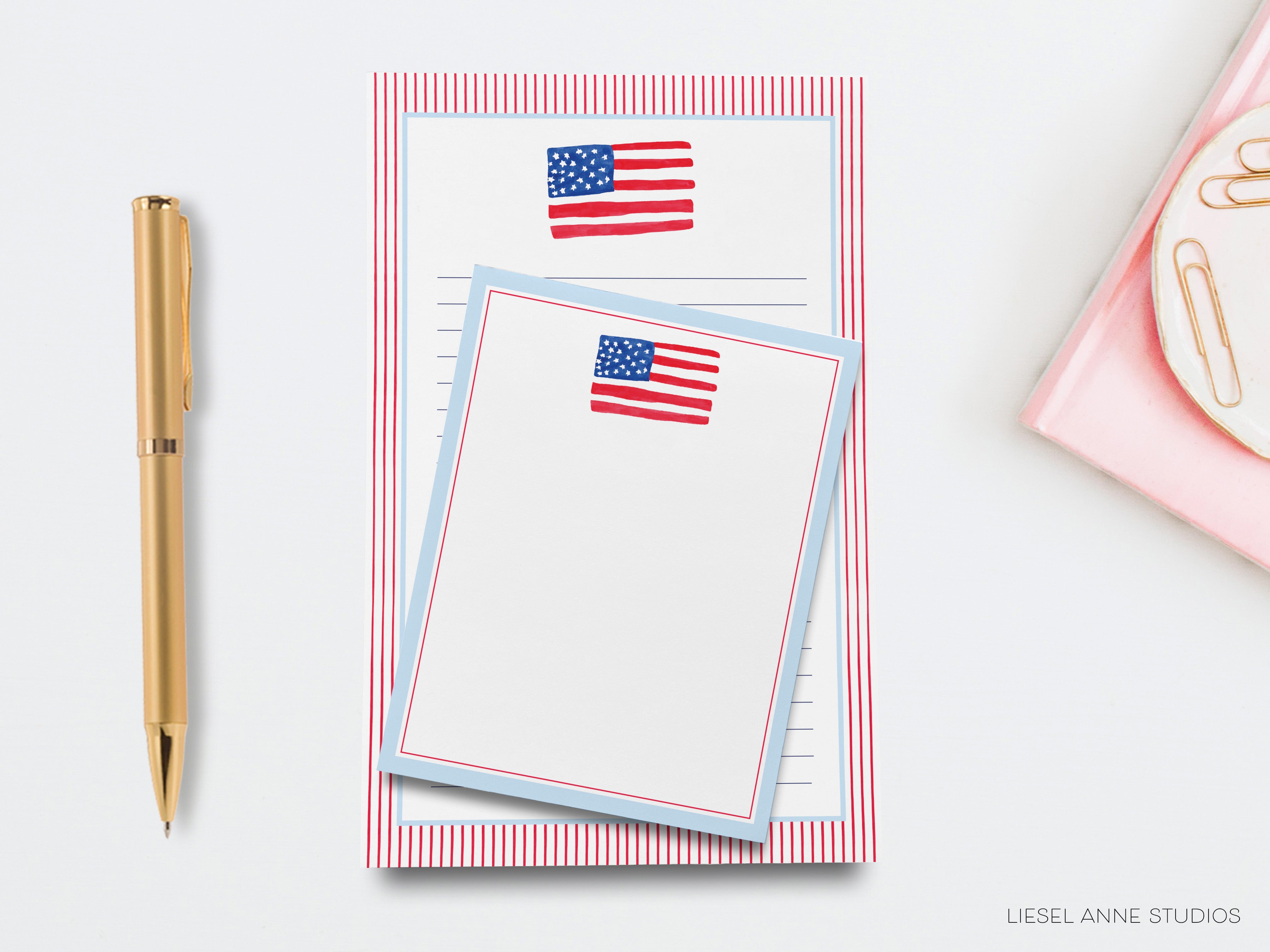 a pen, a stack of blank paper pads with an American flag design, and a pink object on a white background.