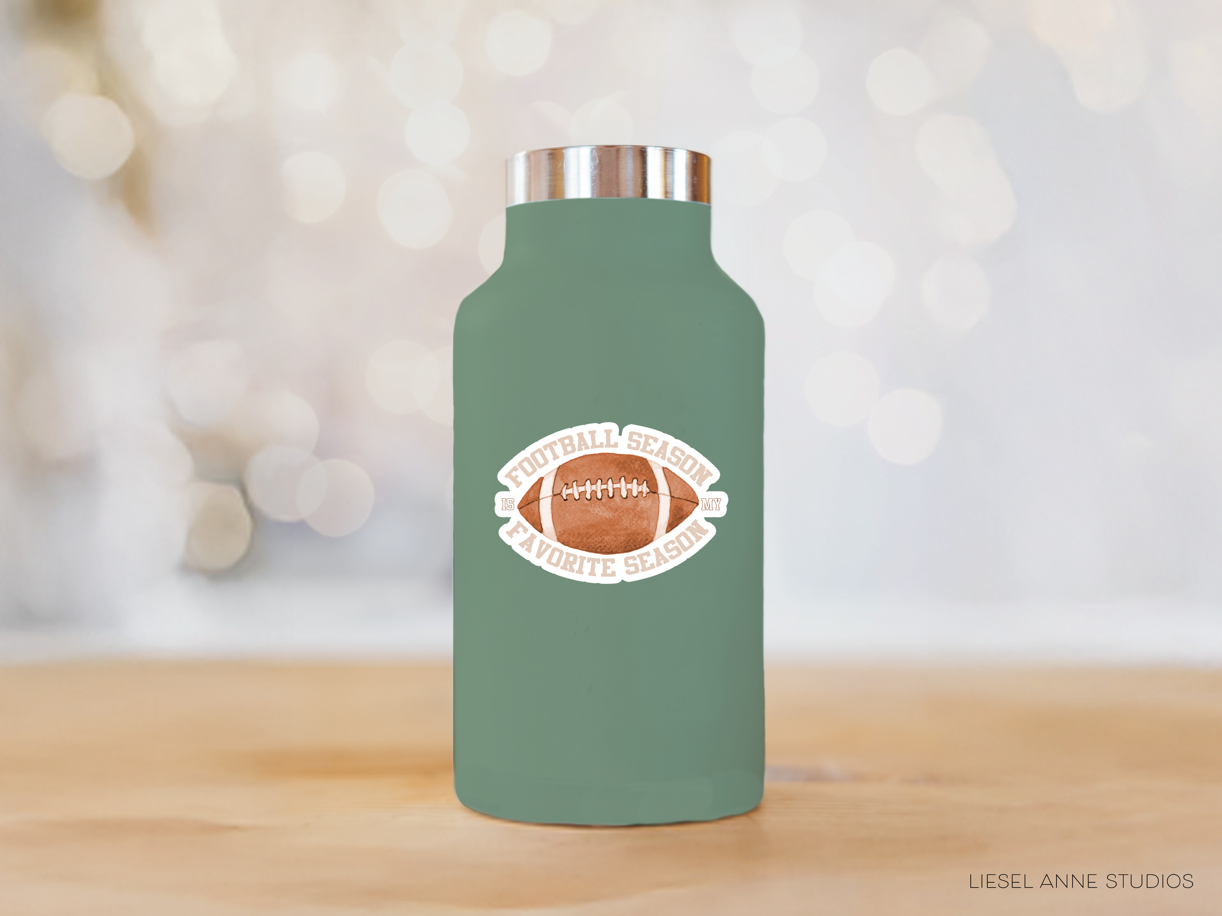 A green thermos bottle with a football design on it, placed on a wooden surface against a blurred background.