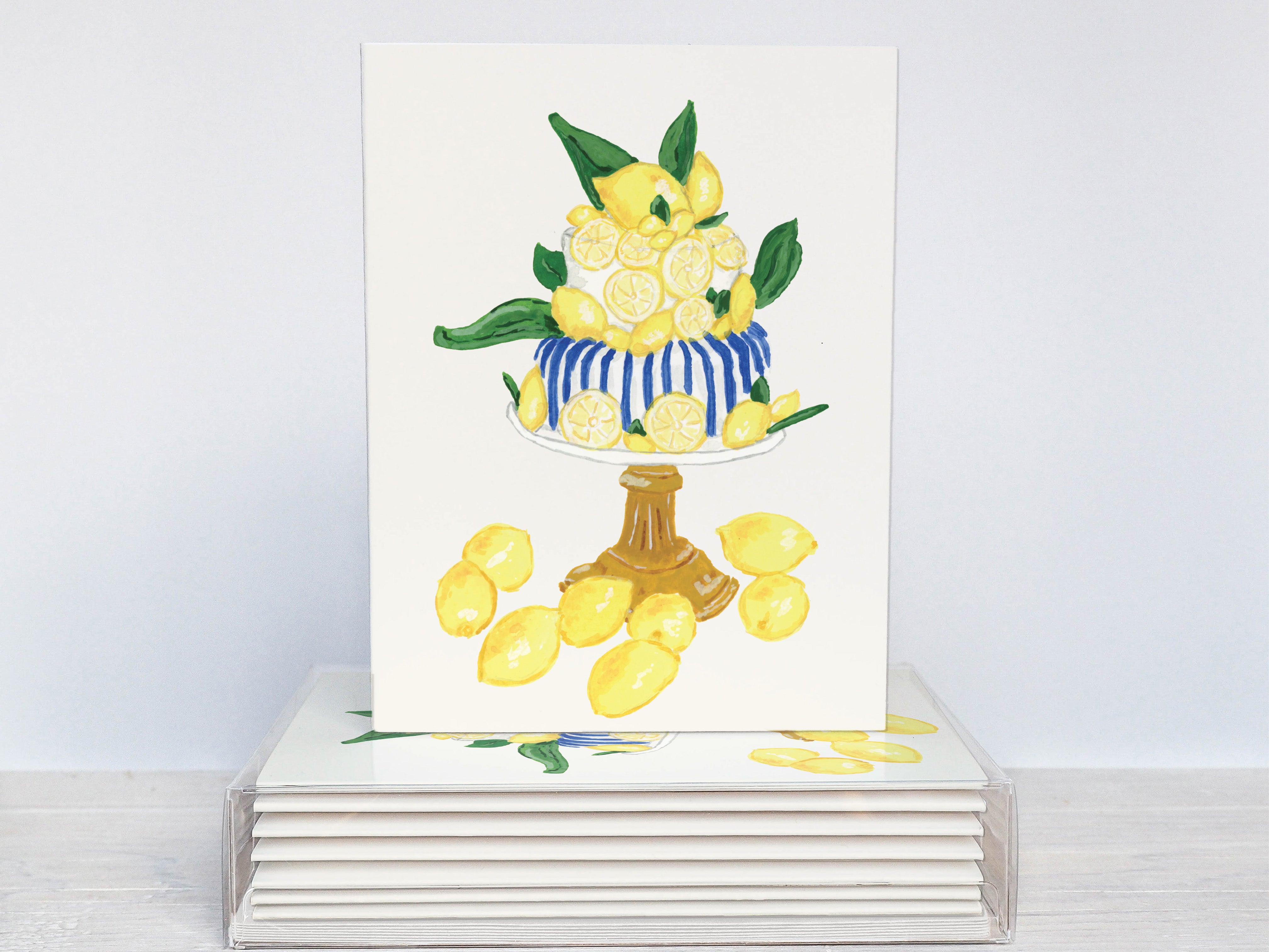 A white card with a vibrant illustration of a lemon cake on top, surrounded by numerous lemon slices.