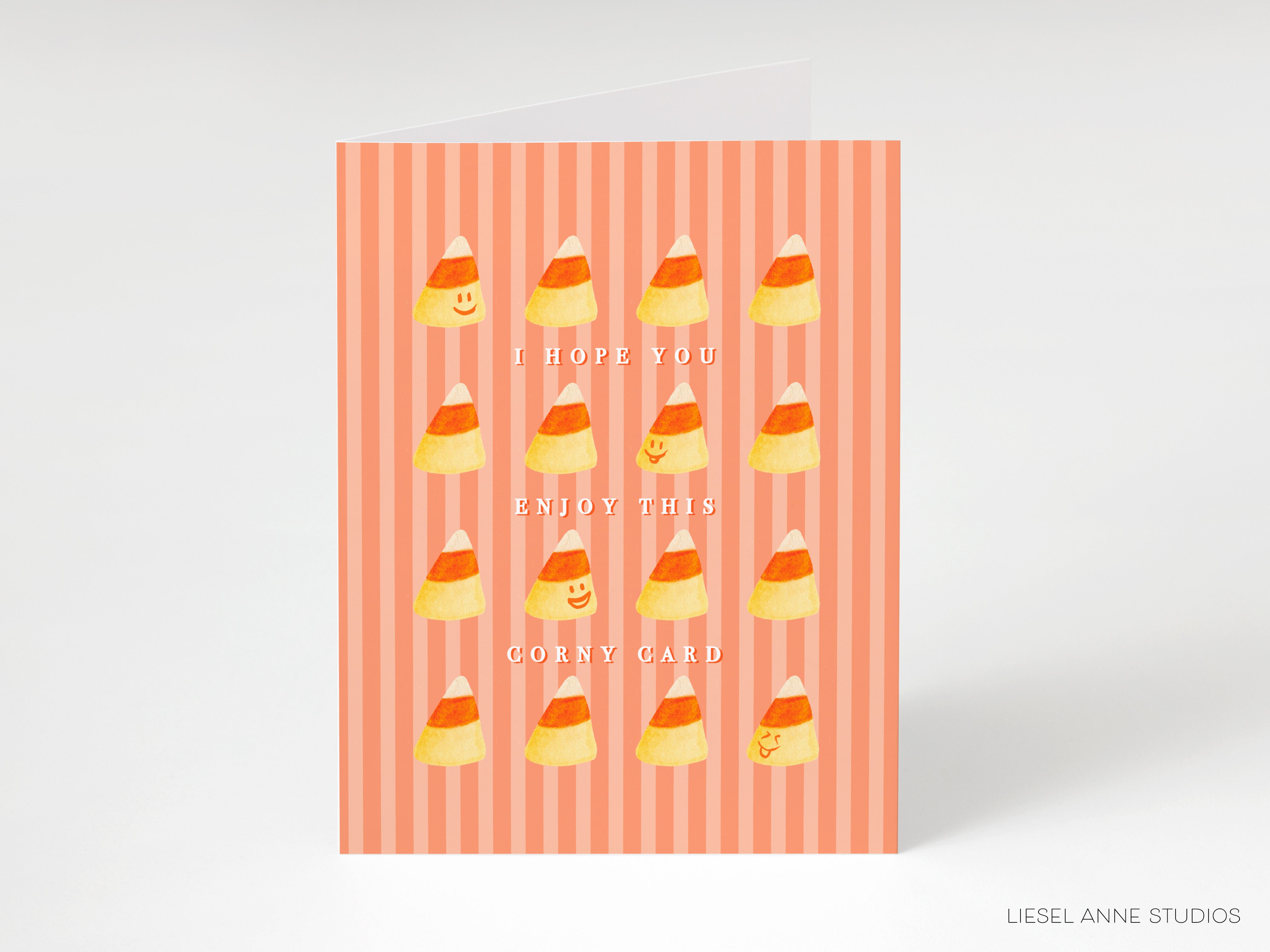 The image is a greeting card with a striped background and a playful design featuring candy corn illustrations. The card has a message that reads "I hope you enjoy this corny card" and is presented in a visually appealing and colorful manner.
