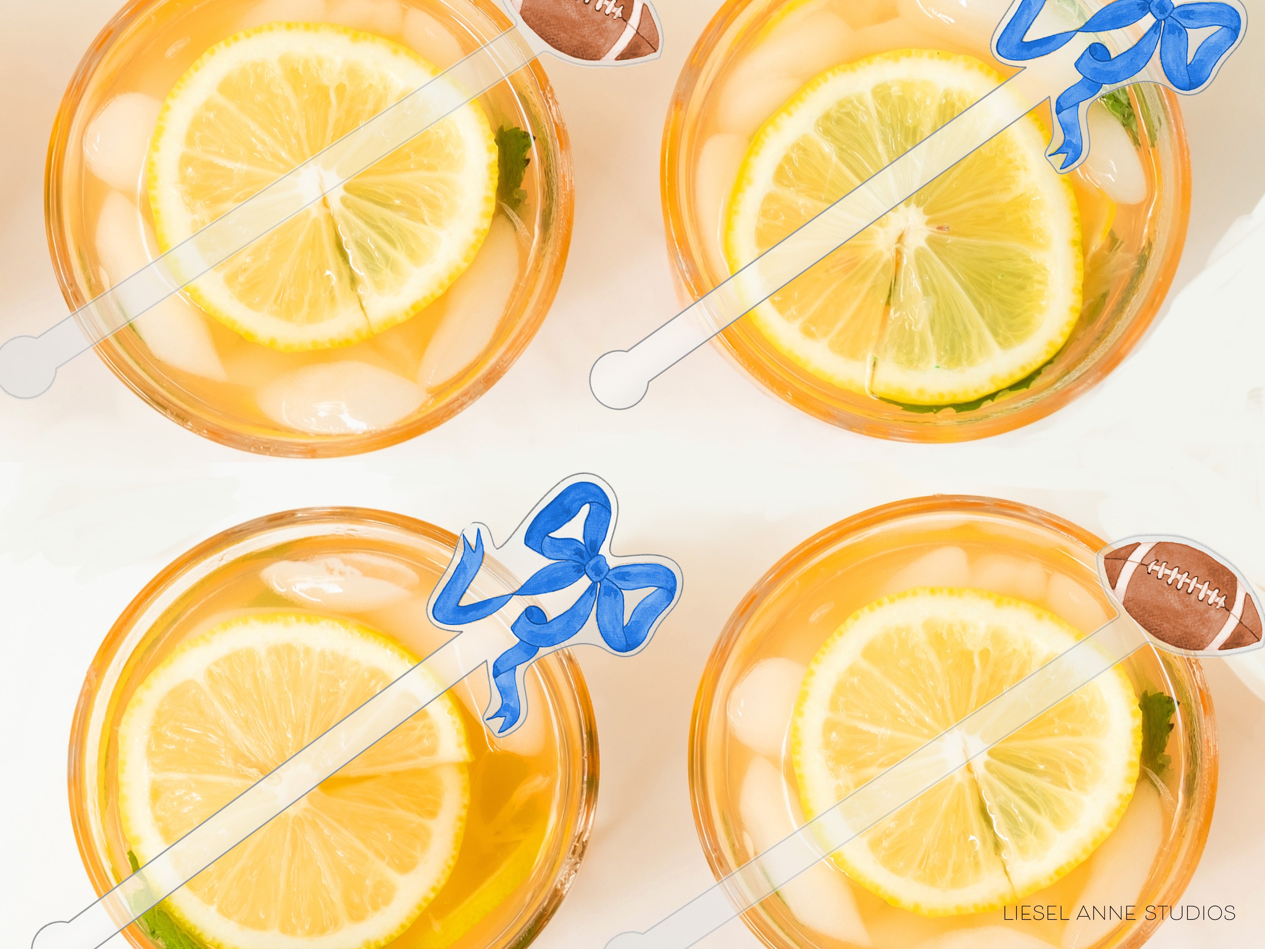 four glasses filled with a yellow liquid, each containing a slice of lemon and a blue ribbon.