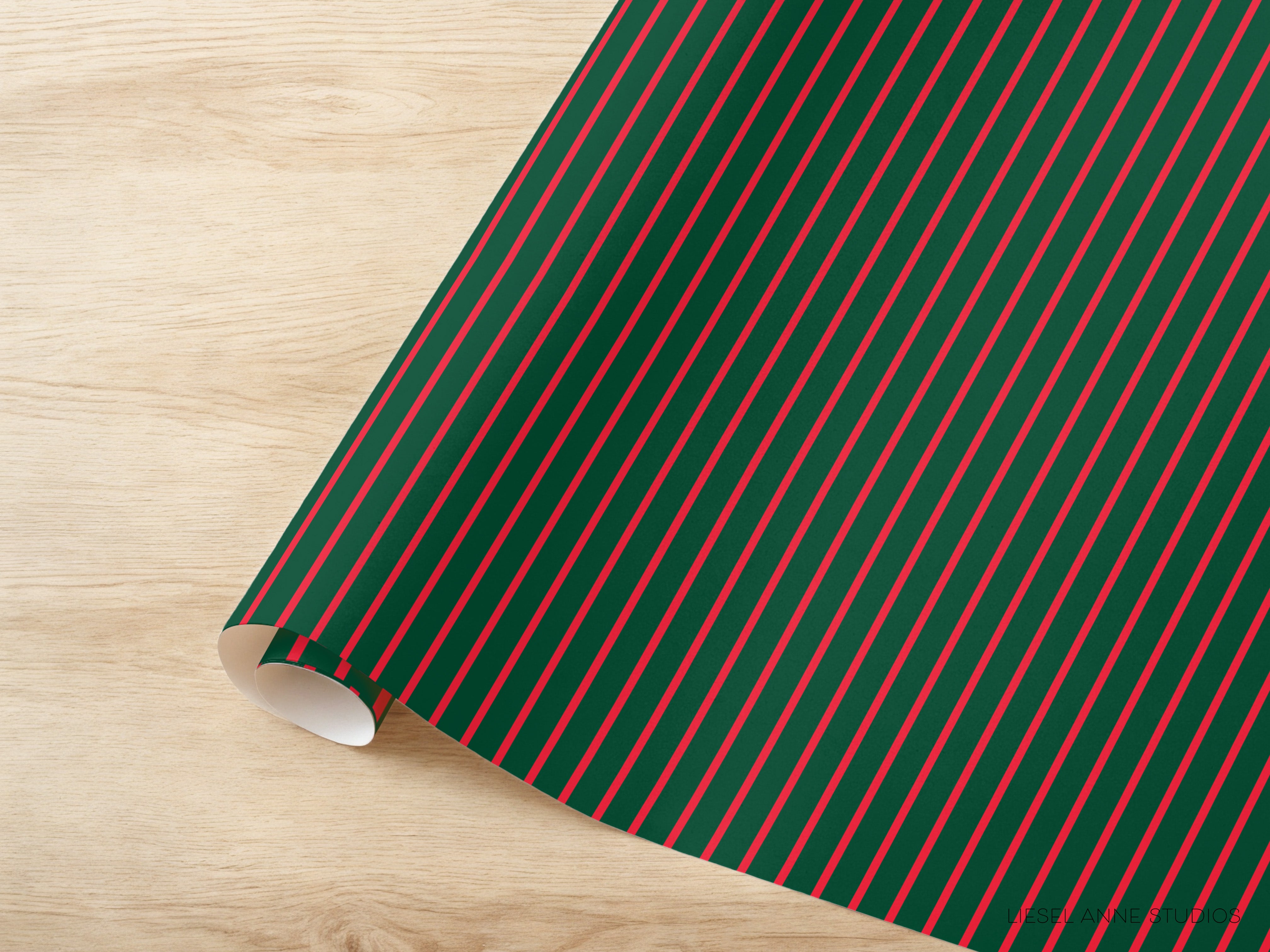 A roll of green and red striped wrapping paper is placed on a wooden surface.