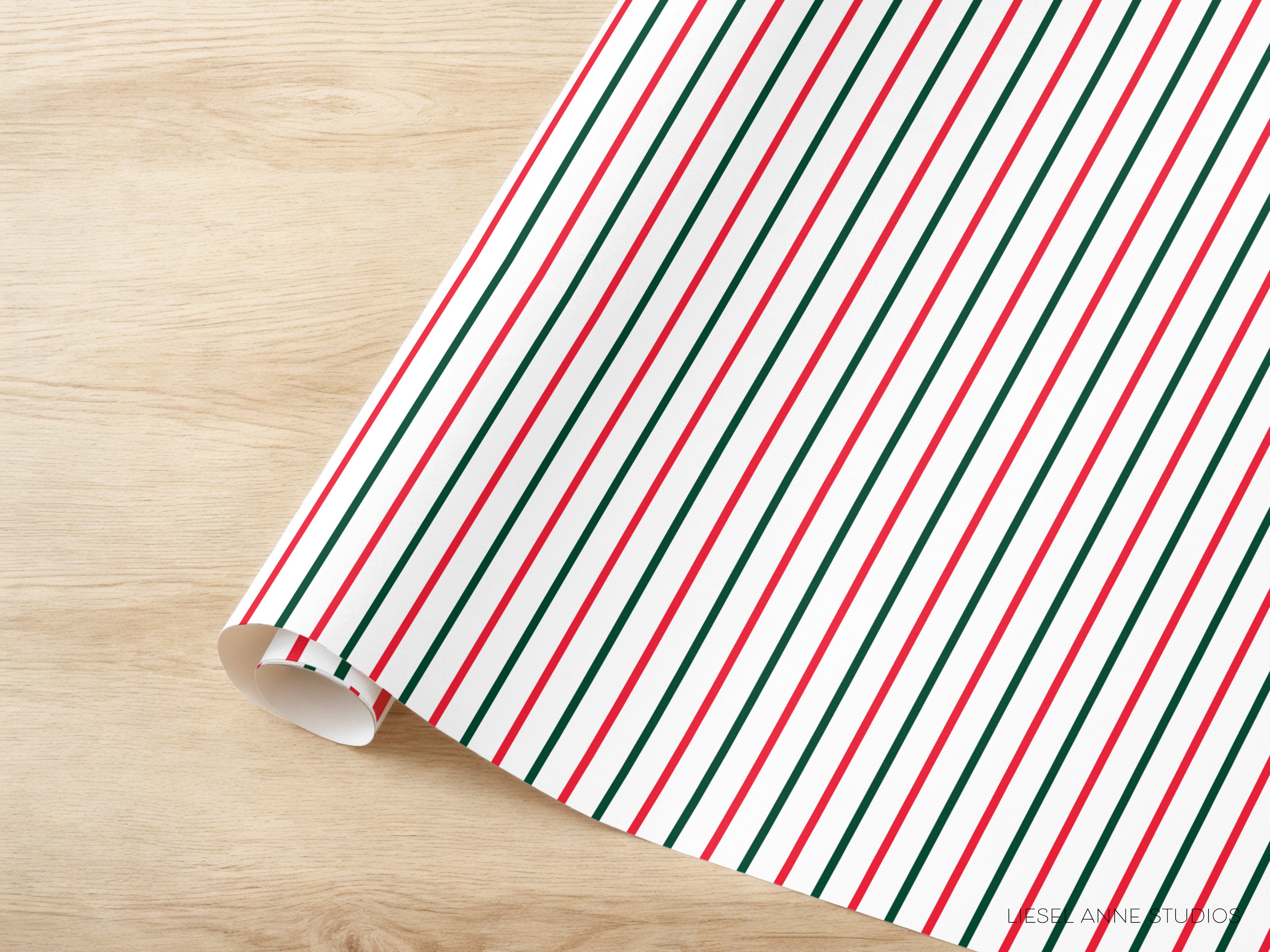 A roll of wrapping paper with a striped pattern in red, green, and white colors is placed on a wooden surface.