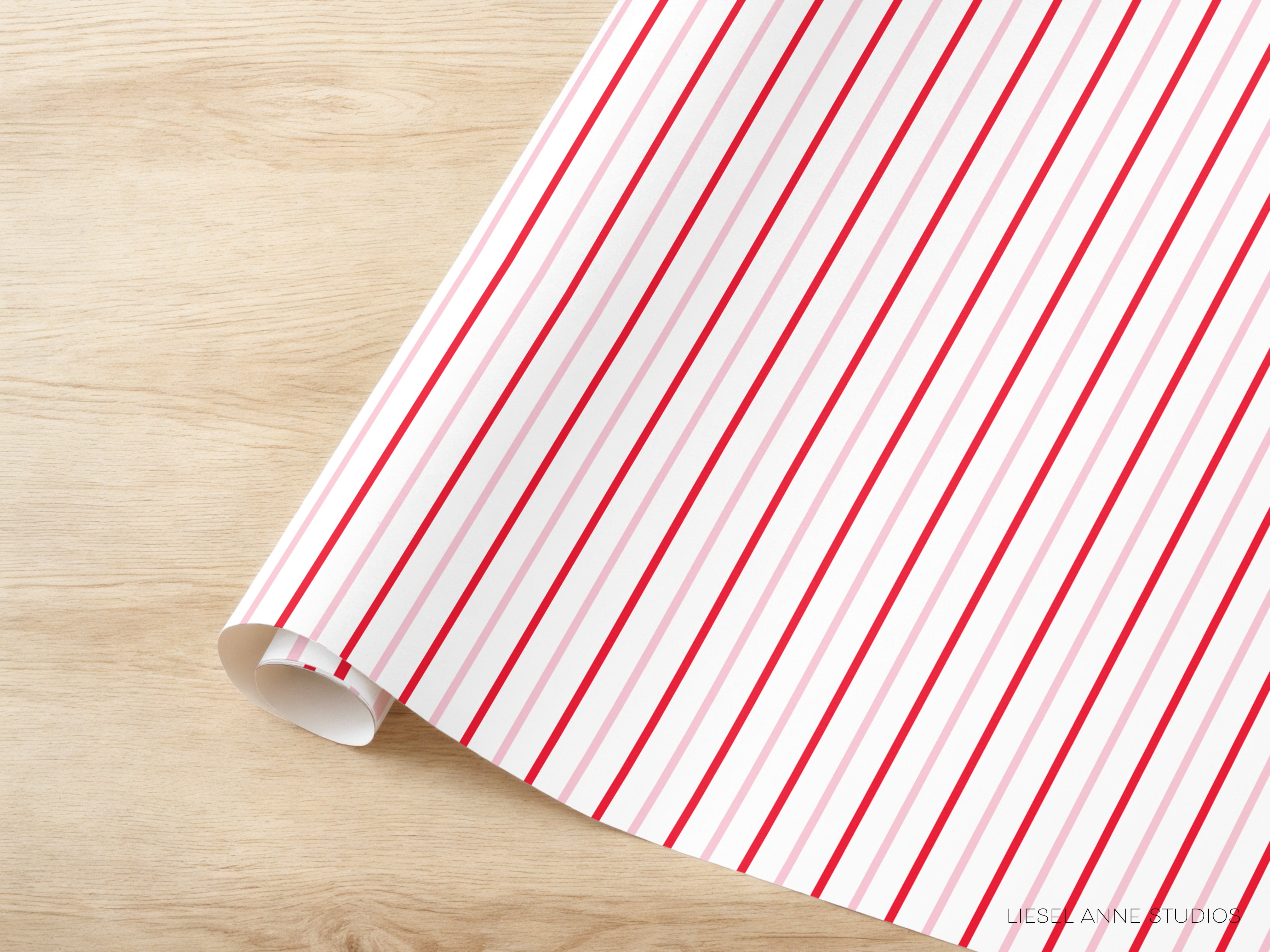A roll of red and white striped paper is placed on a wooden surface.
