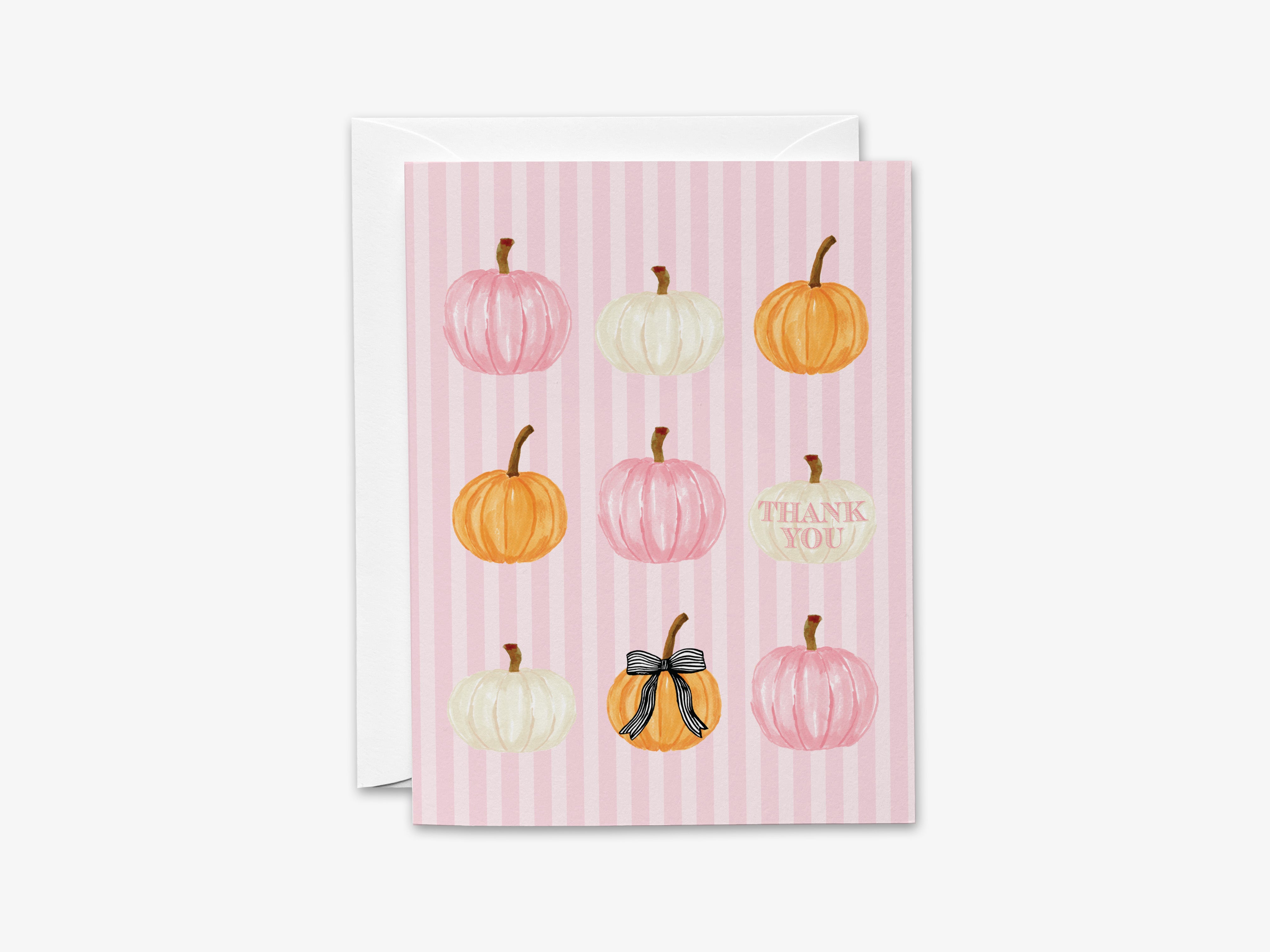 A pink striped card with nine pumpkins of various sizes and colors, including white, orange, and black bows, arranged in a grid pattern.
