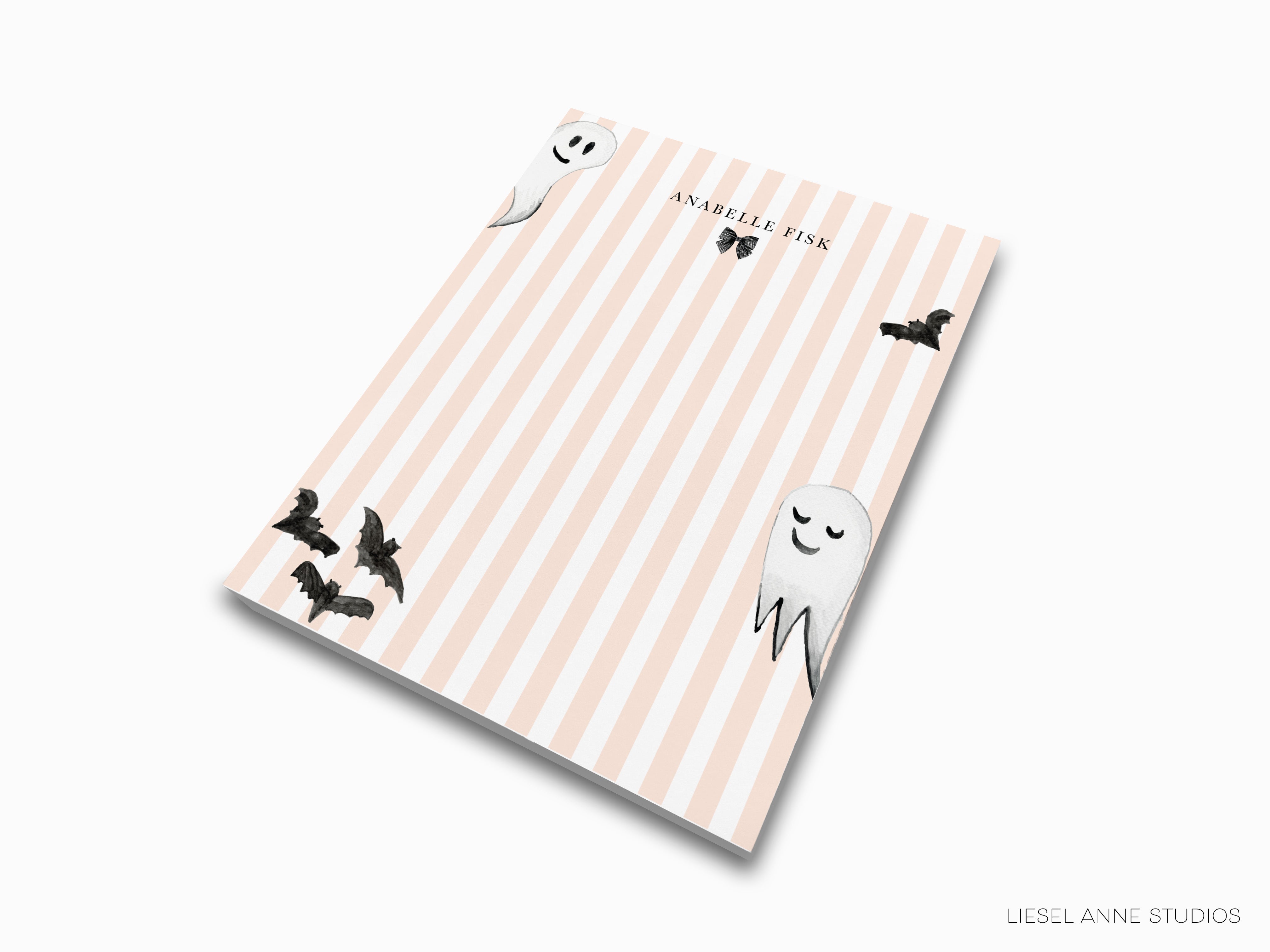 a notebook cover with a striped background and illustrations of bats and a smiling ghost.