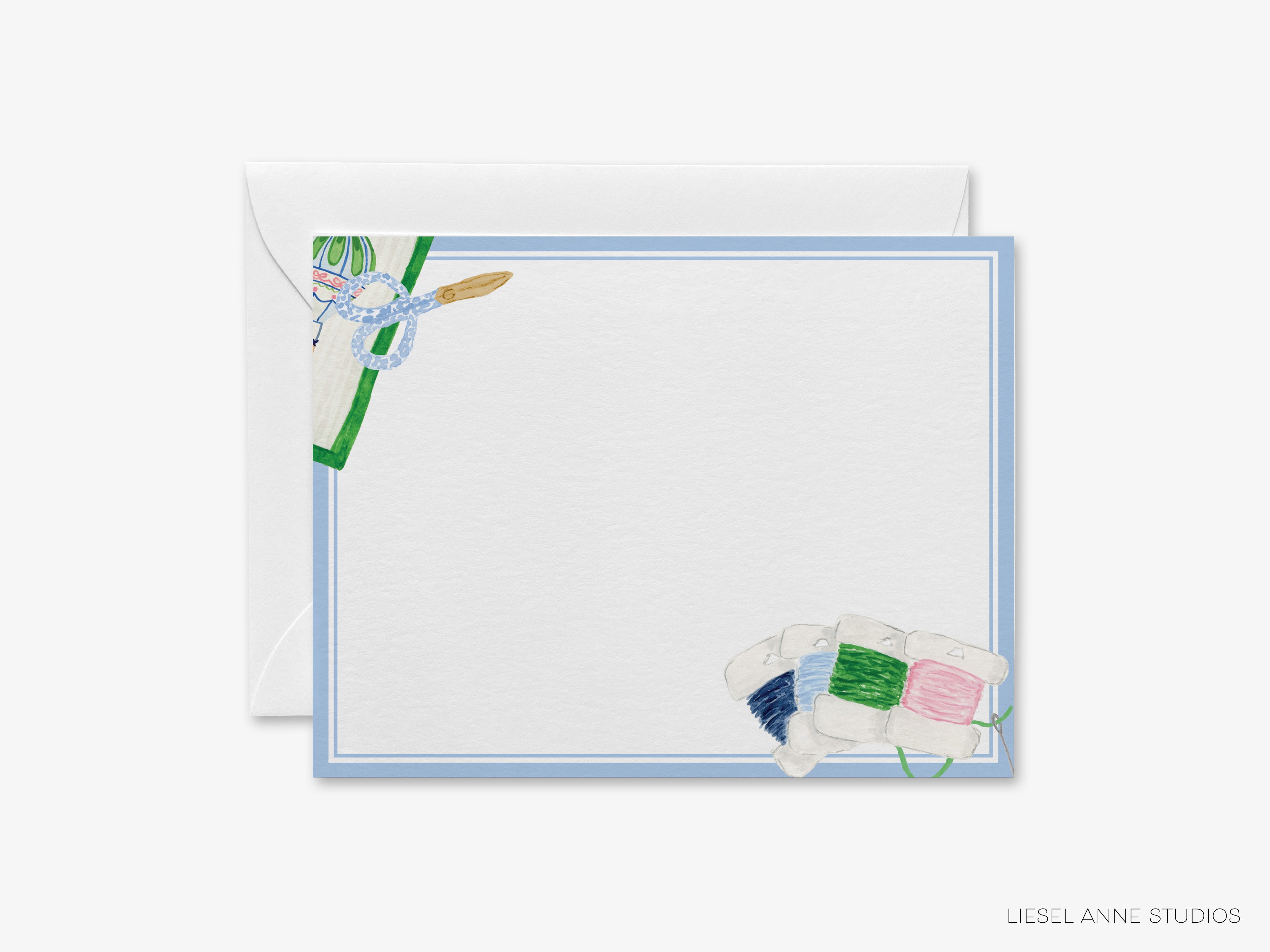A blank card with a blue border and illustrations of sewing supplies, including spools of thread and a needle, is shown in the image.