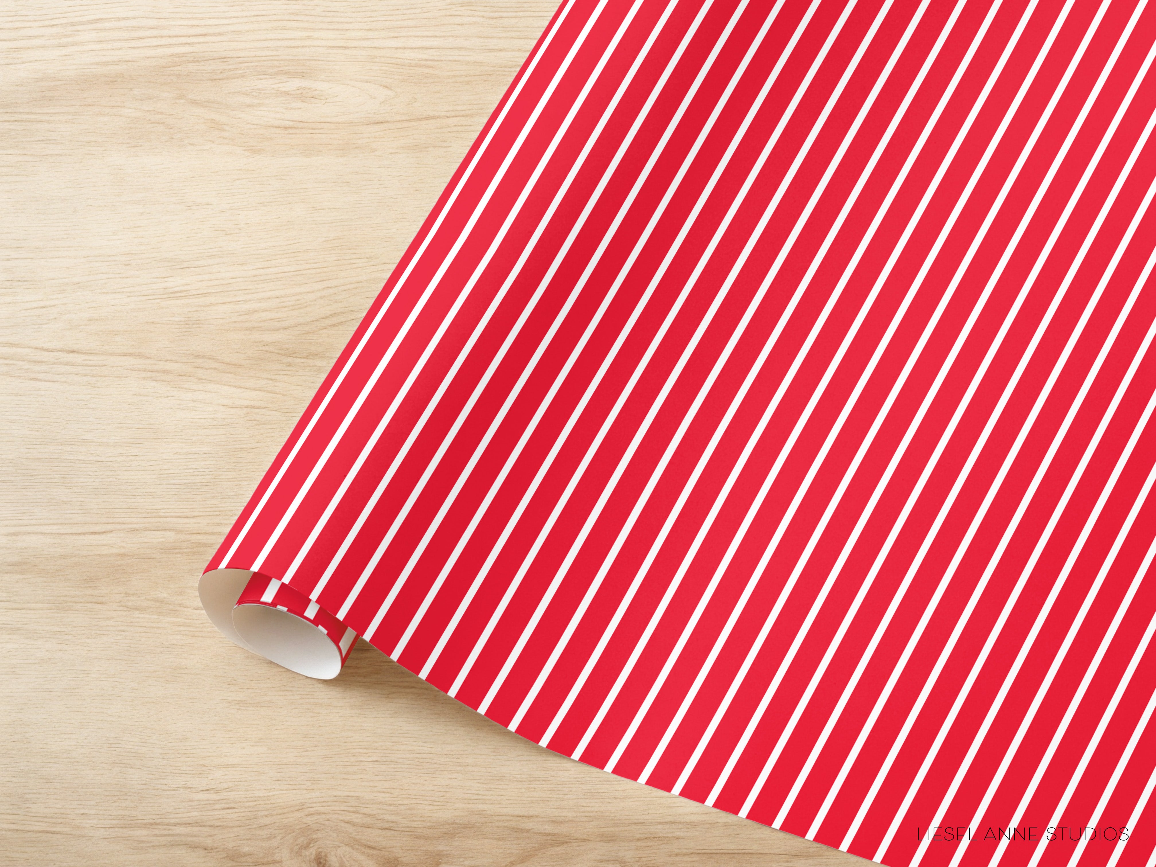 A roll of red and white striped wrapping paper is placed on a wooden surface.