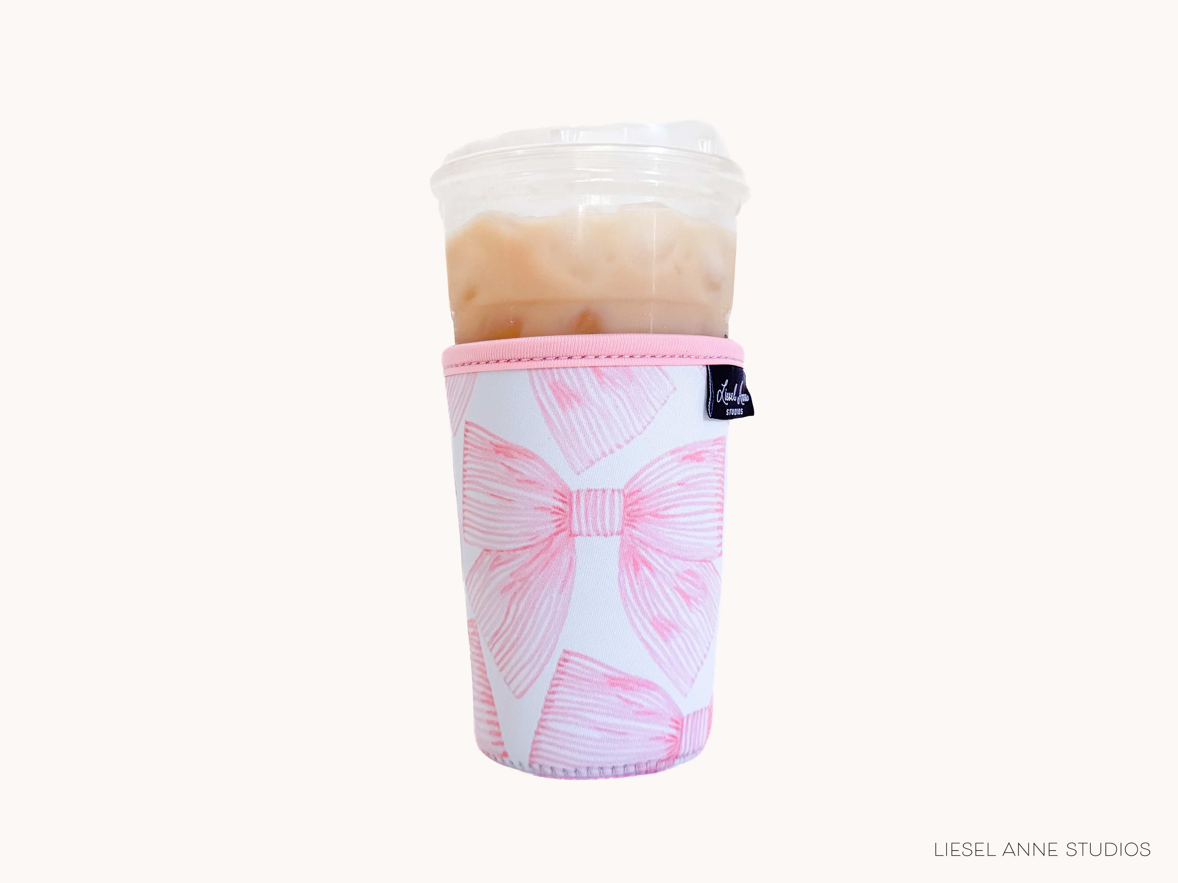 A pink and white cup holder with a bow design, containing a beverage.