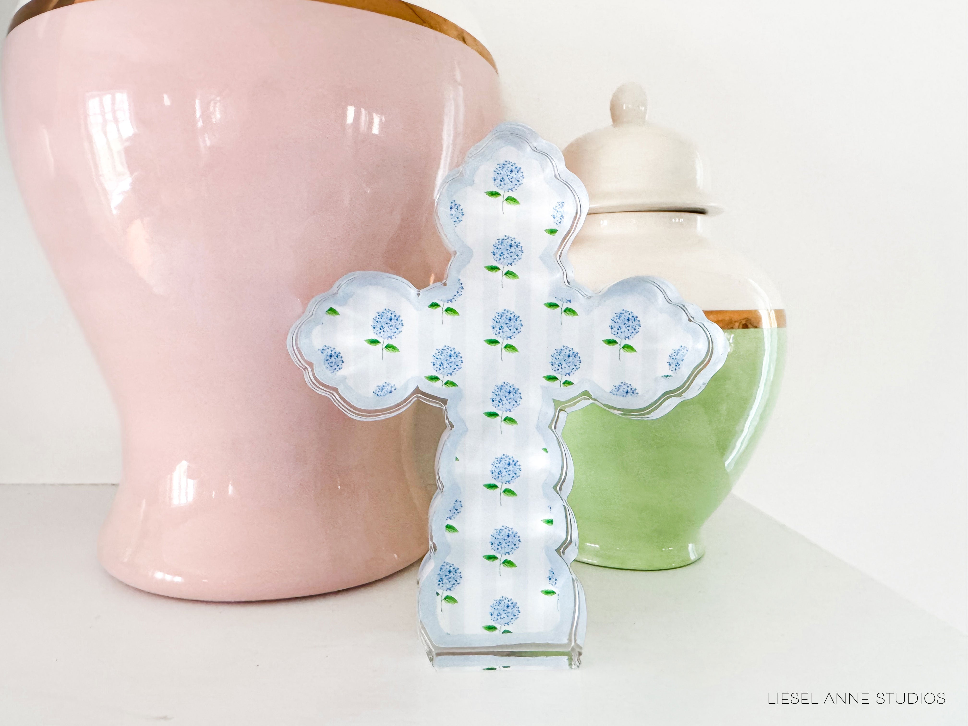 a ceramic cross sitting next to a pink vase