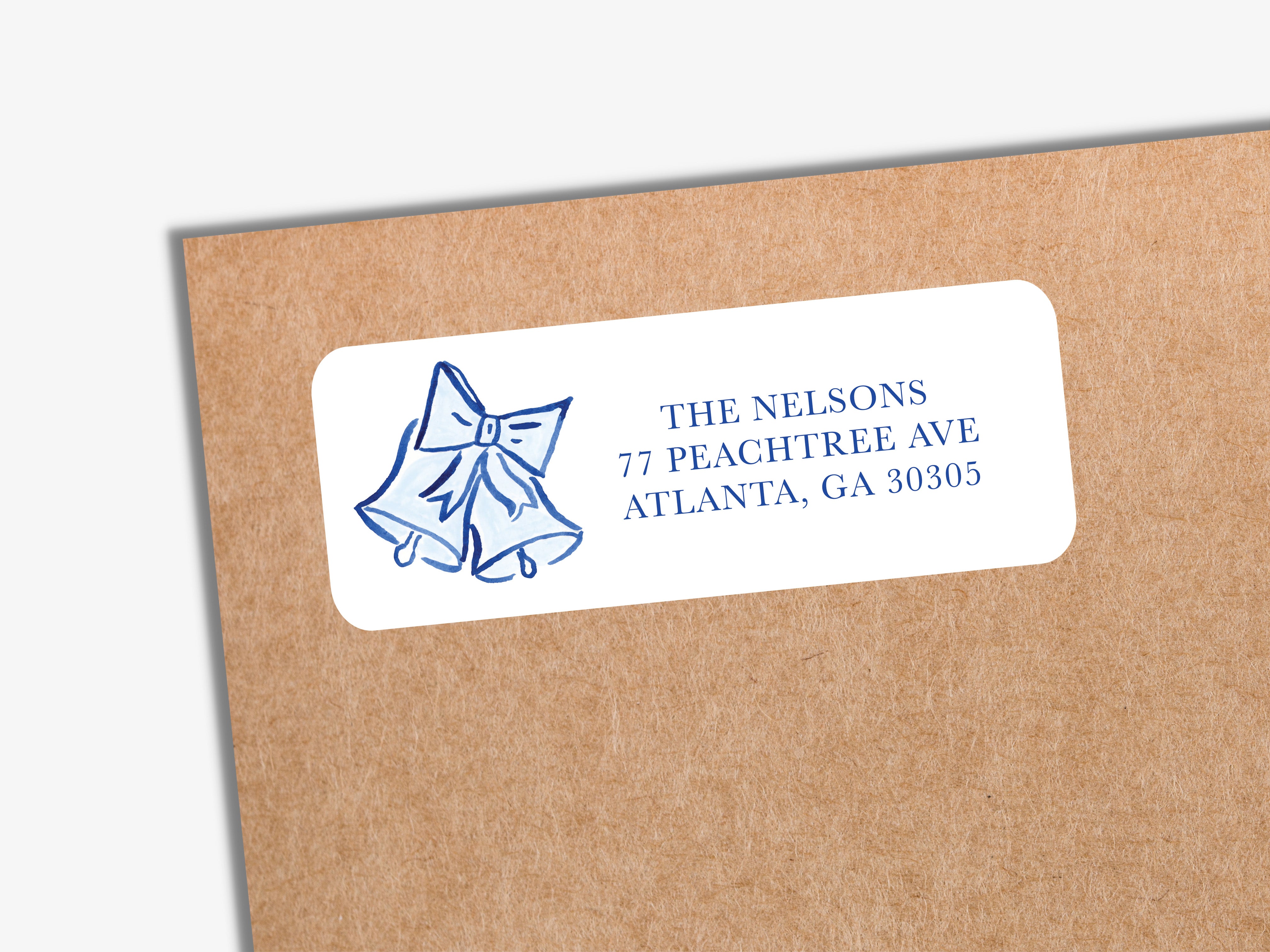 The image is a label with a blue bow and bells on it, placed on a brown envelope.