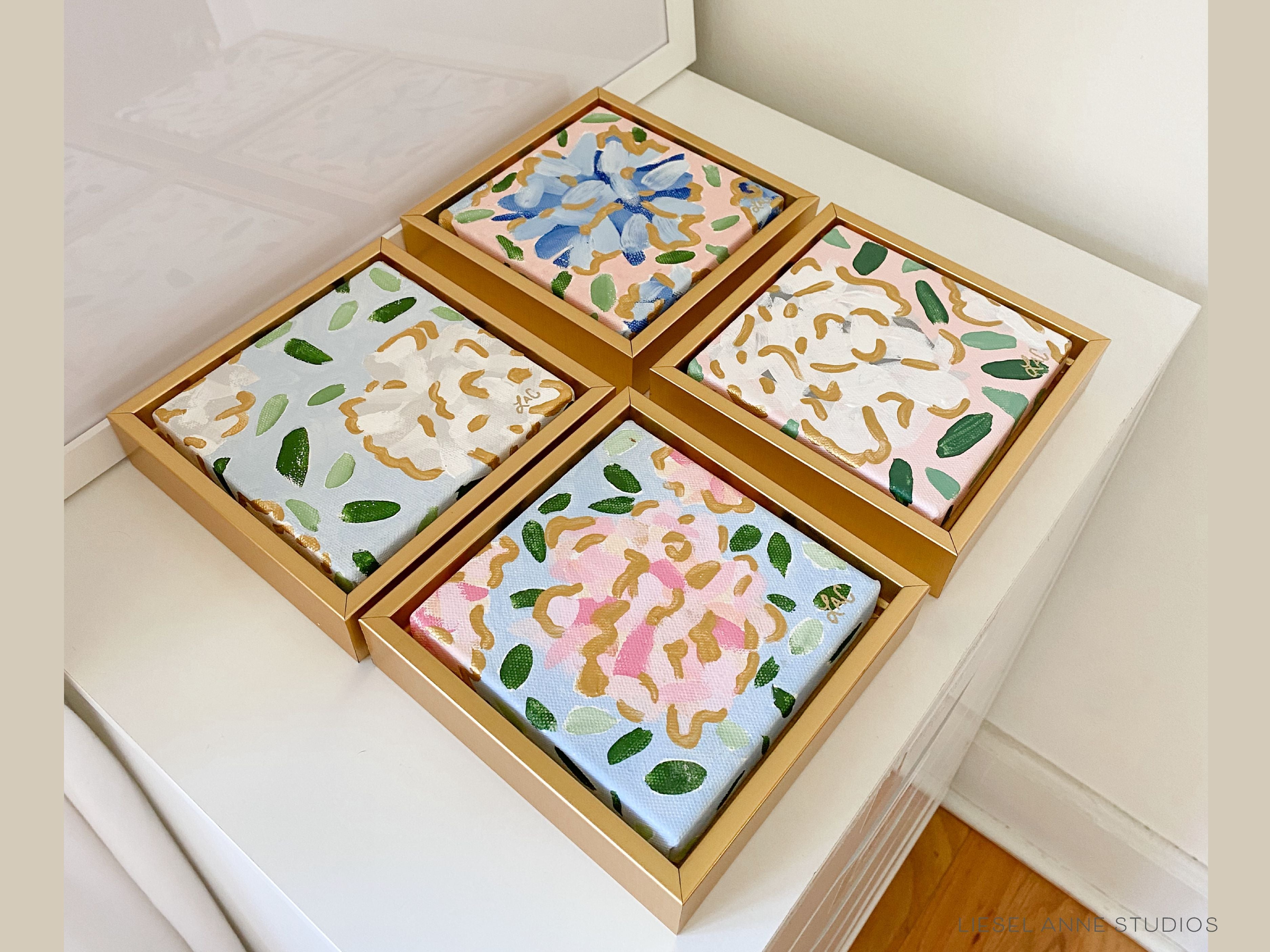 Golden Hydrangea Mini | Blue & Pink XVII-Original artwork measures 5"x5" | Framed in gold wood floater frame | Hand-Painted with gouache on stretched canvas | Features our signature Golden Hydrangea design with a light blue base, pink hydrangeas and shimmery gold accents | Initialed in gold by the Liesel Anne (the artist) on the front and signed and dated on the back-The Singing Little Bird