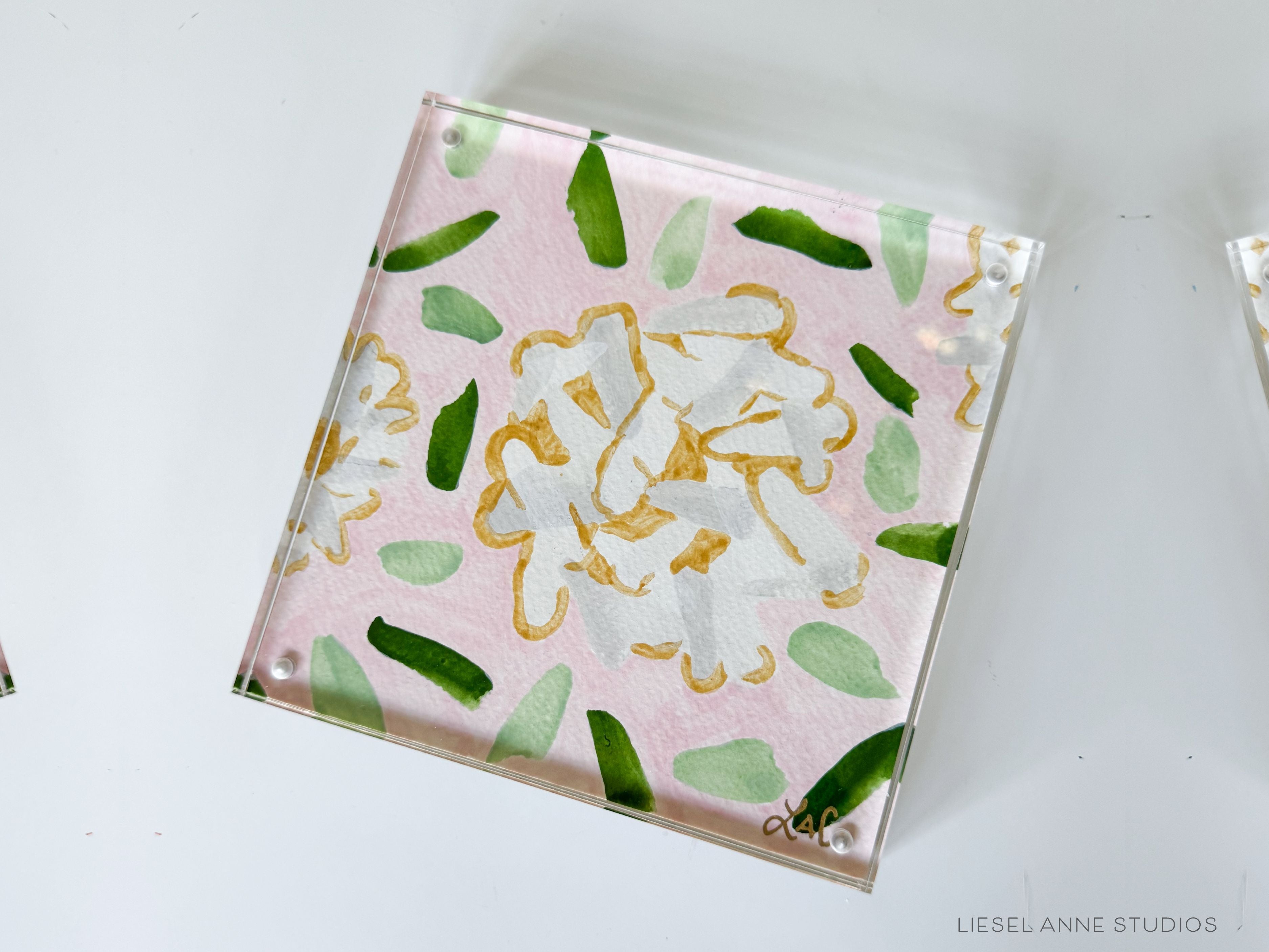 Golden Hydrangea Mini | Pink & White 02-Original artwork measures 6"x6" | Hand-Painted with gouache on cold press watercolor paper | Framed in clear acrylic magnetic block frame | Features our signature Golden Hydrangea design with a pale pink base, white hydrangeas and shimmery gold accents | Initialed in gold by the Liesel Anne (the artist) on the front and signed and dated on the back-The Singing Little Bird