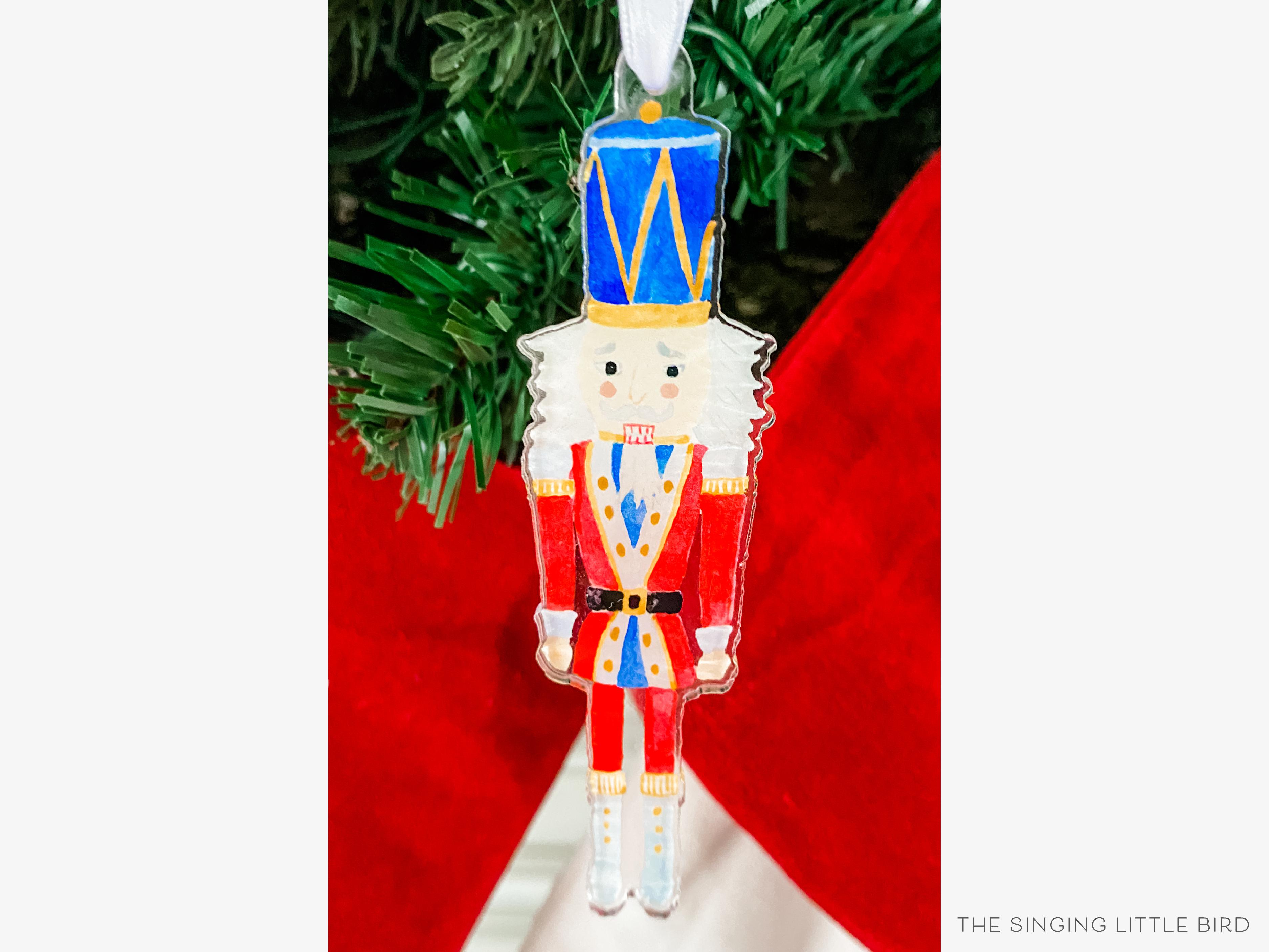 Nutcracker Acrylic Ornament-These acrylic ornaments feature our hand-painted watercolor Nutcracker. They include a white silk ribbon and measure approximately 4" on its longest side, making a great addition to your Christmas tree or gift for the Nutcracker lover in your life.-The Singing Little Bird