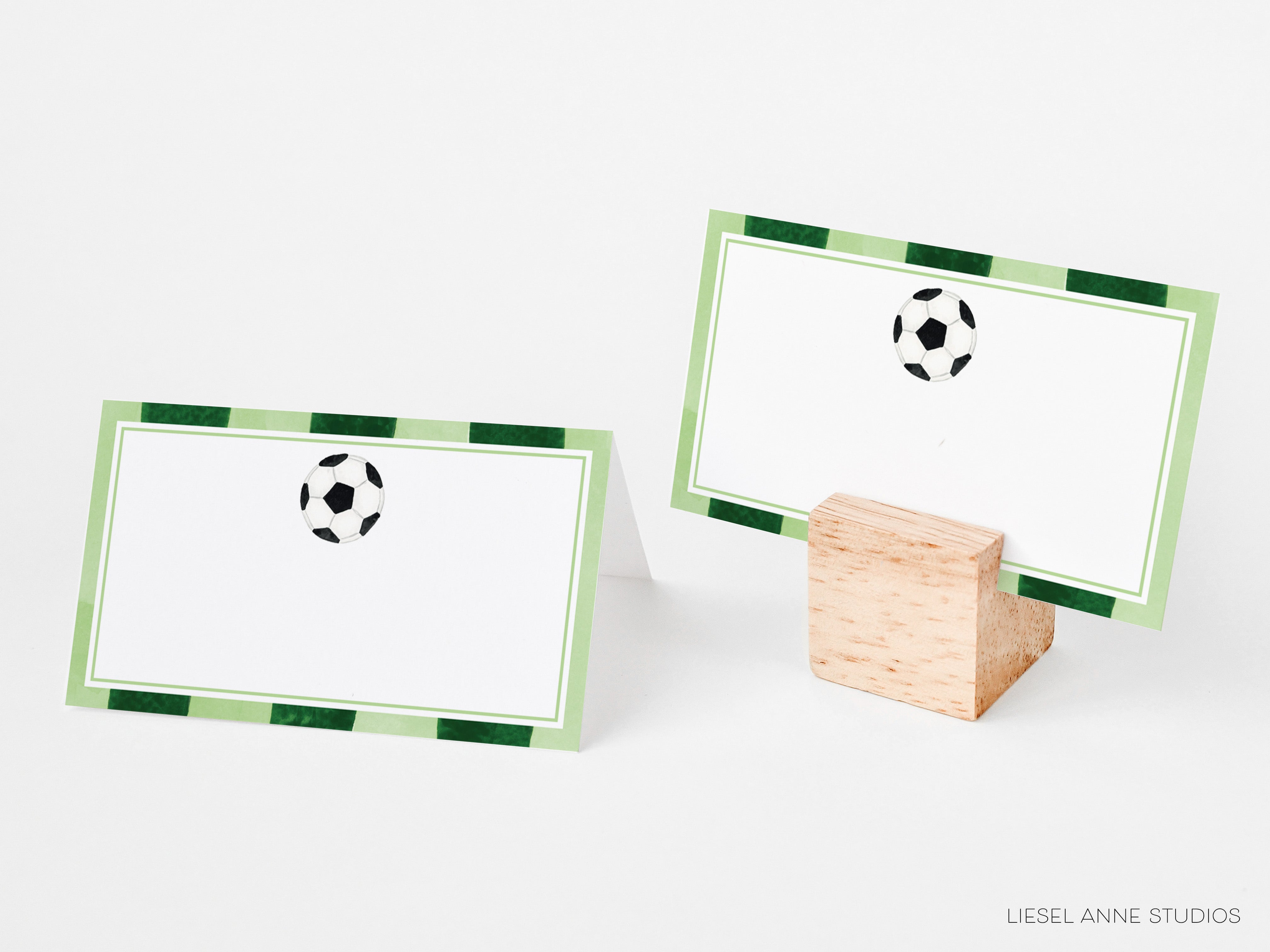 two place cards with a soccer ball design on them, placed on a wooden stand.