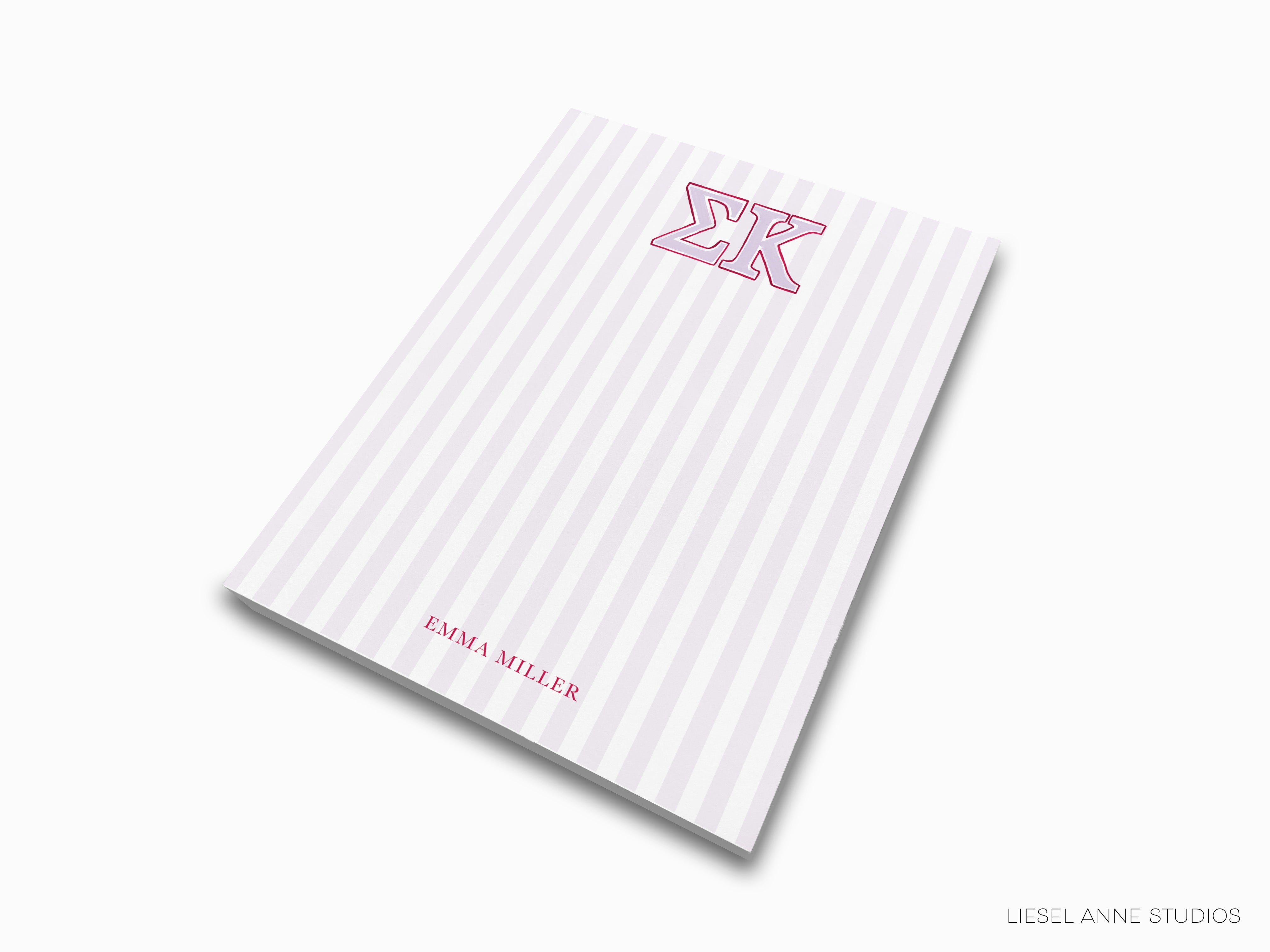 a pink and white striped notebook with the letter k on it