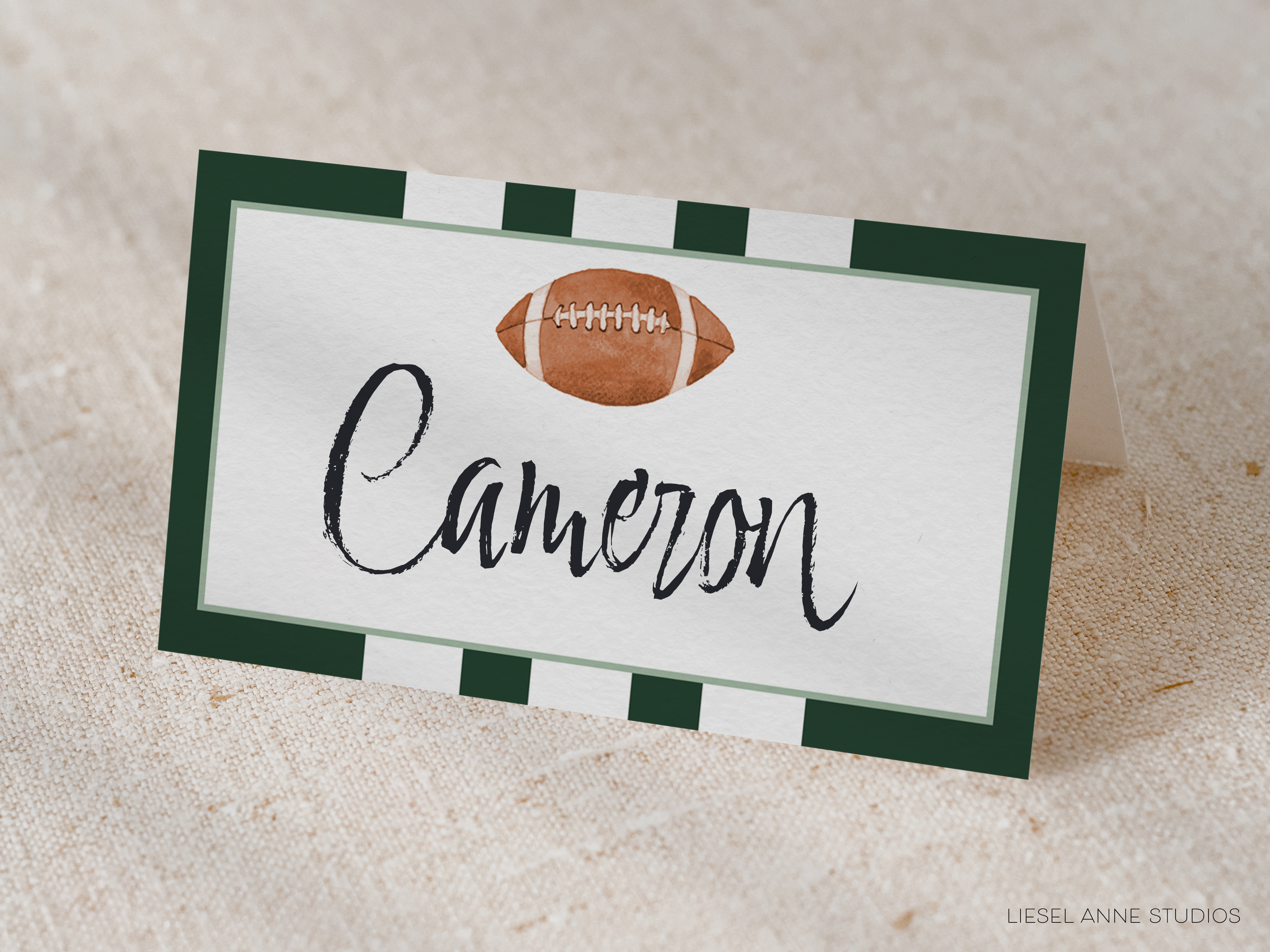 A name card with a football on it, placed on a beige fabric background.