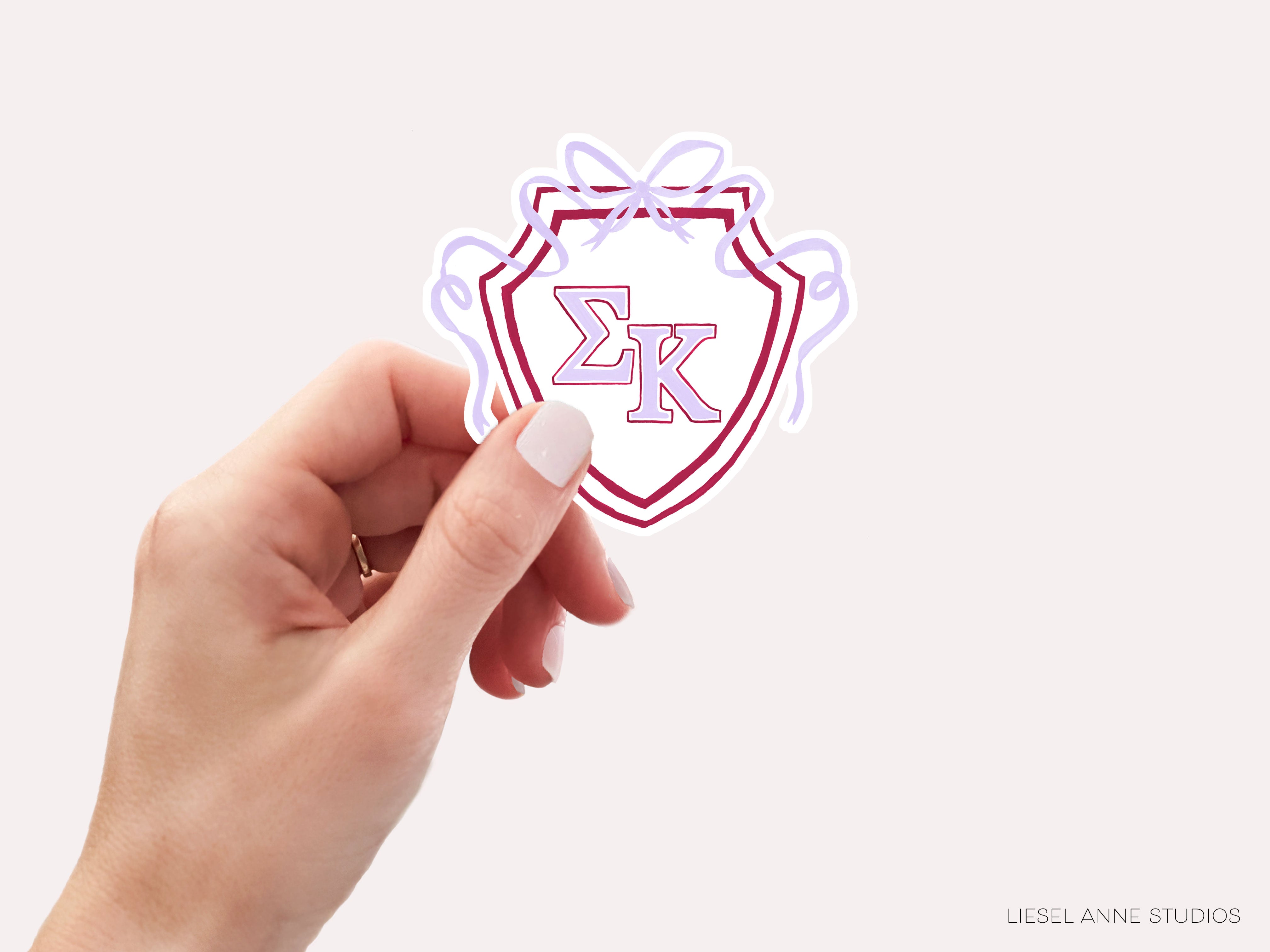 a hand holding a sticker with the letter k on it
