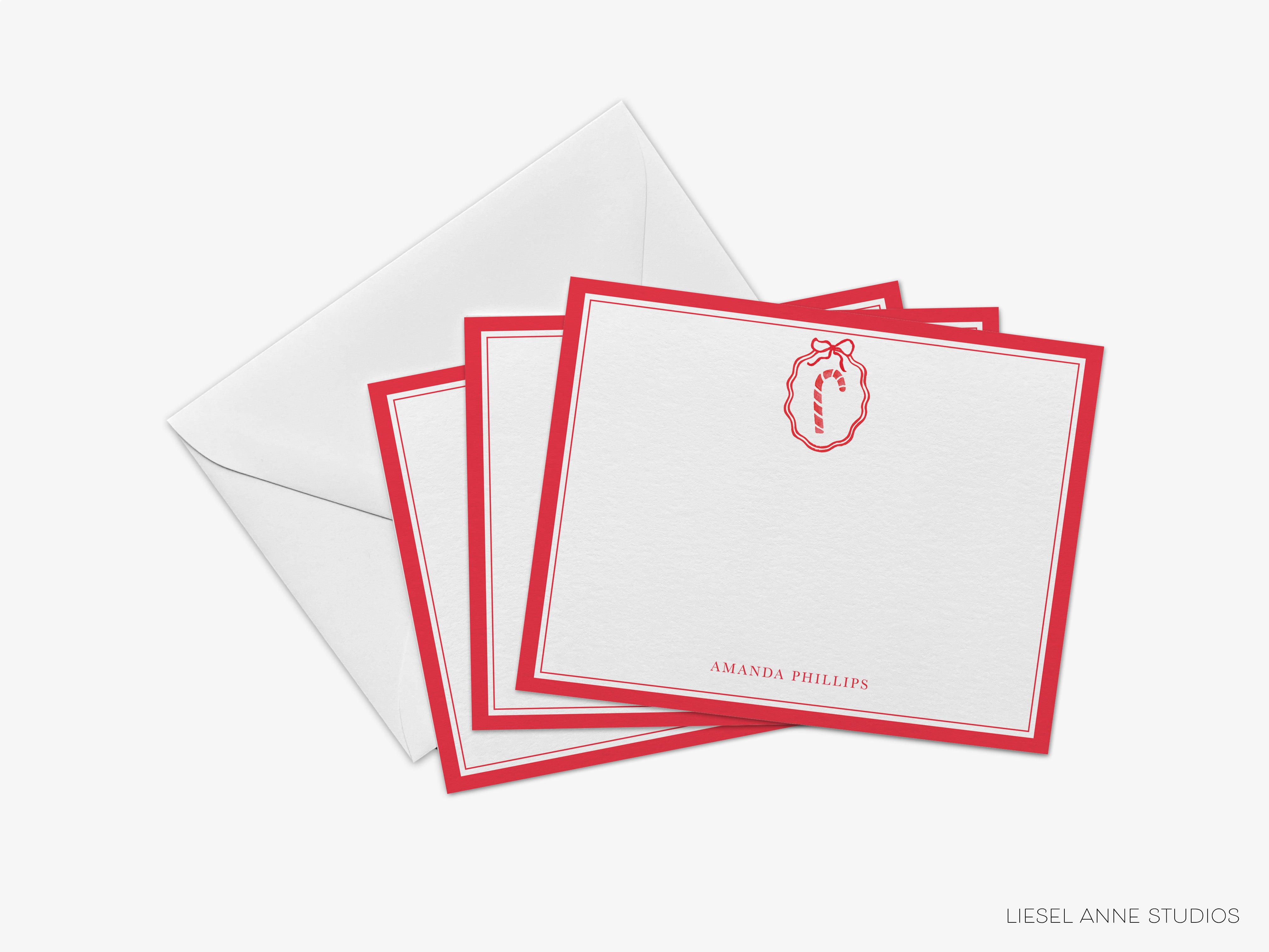 a set of red and white stationery cards with a red ribbon and a red candy cane design, placed on top of an envelope.