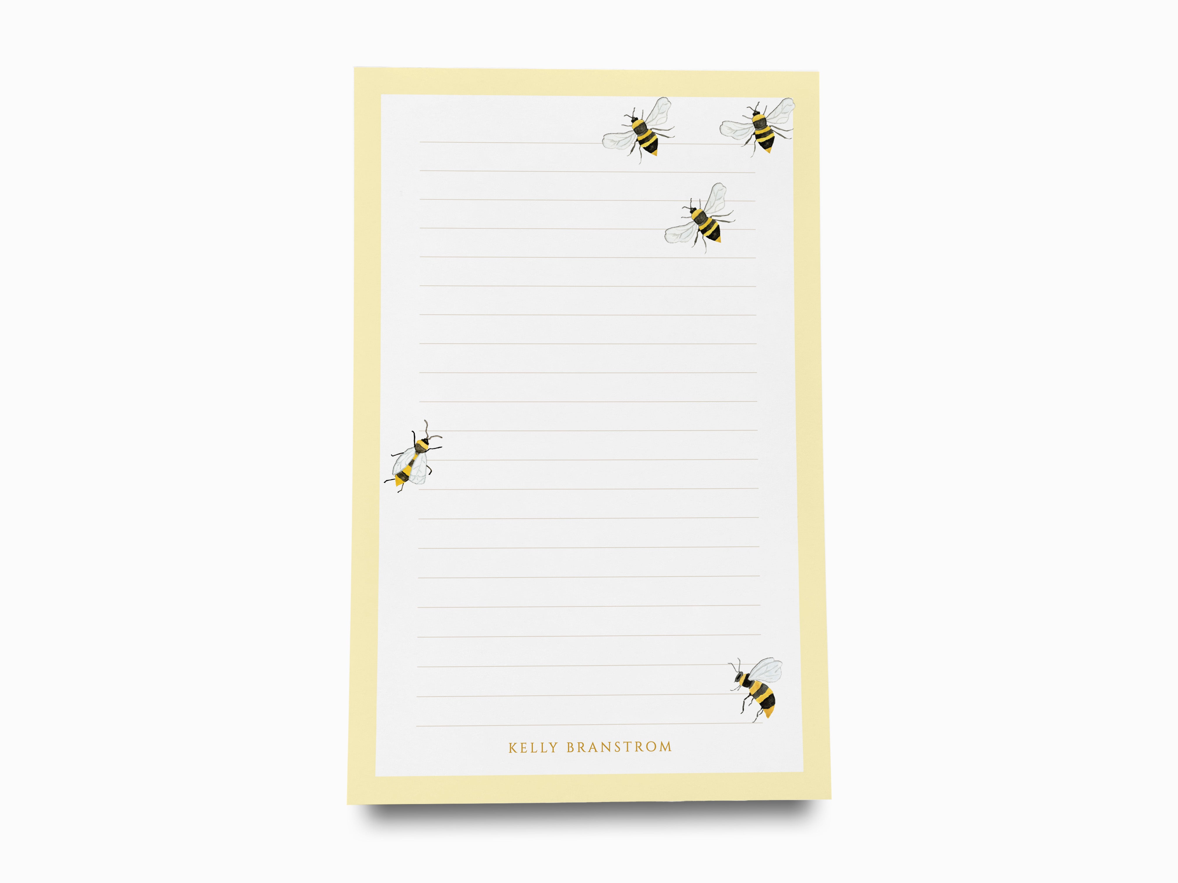 a yellow lined paper pad with a playful design of four bees on it.