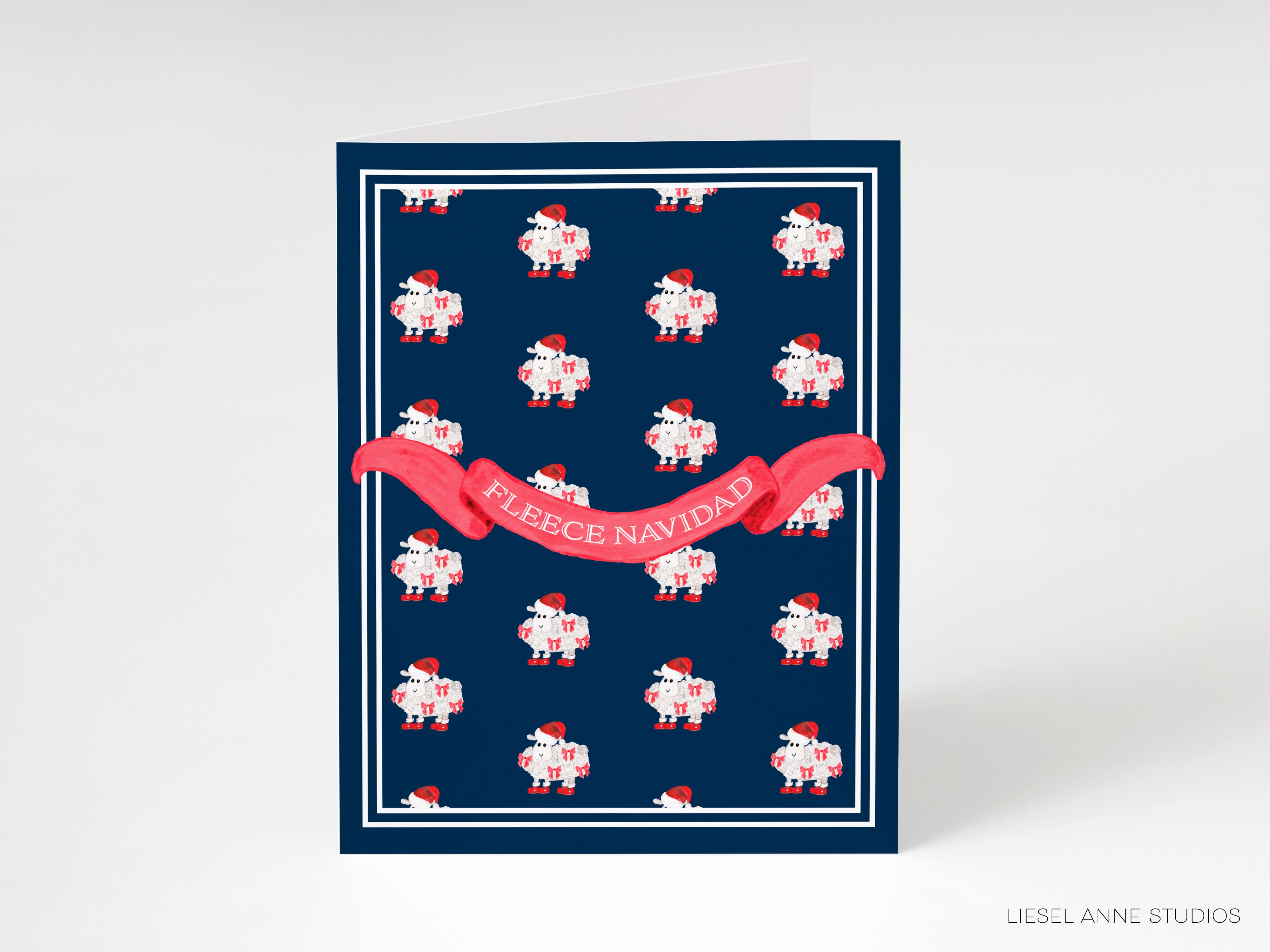 A greeting card with a navy blue background and a repeating pattern of red and white sheep wearing Santa hats. The card has a red ribbon with the text "FLEECE NAVIDAD" written on it.