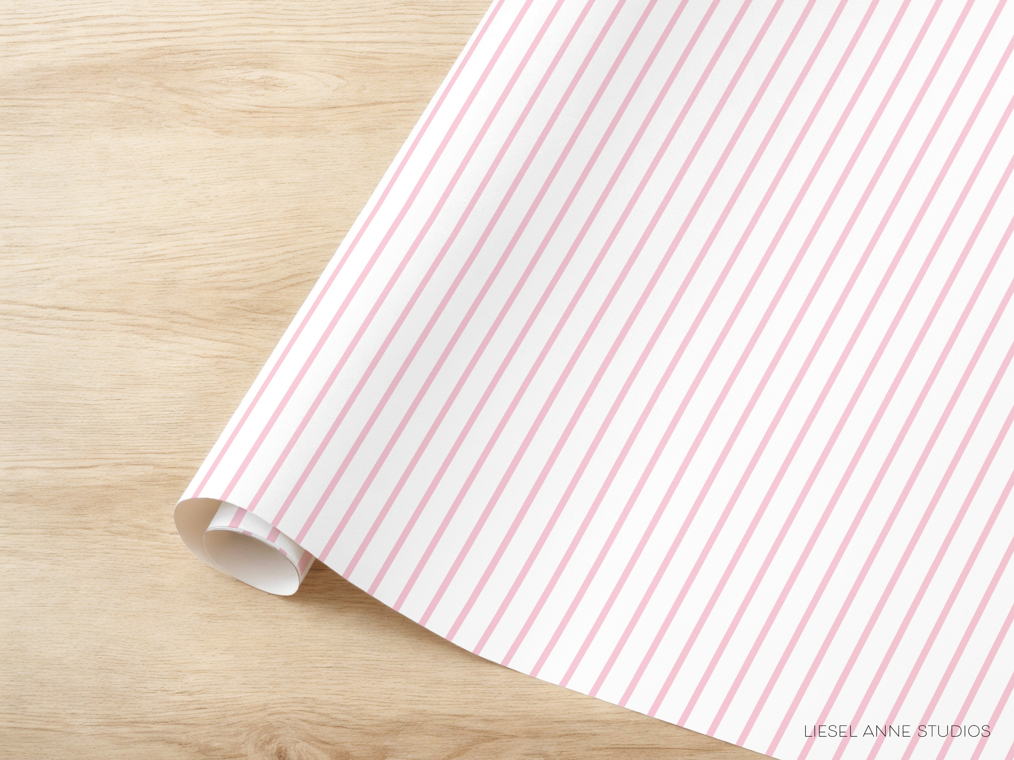 A roll of pink and white striped paper is placed on a wooden surface.