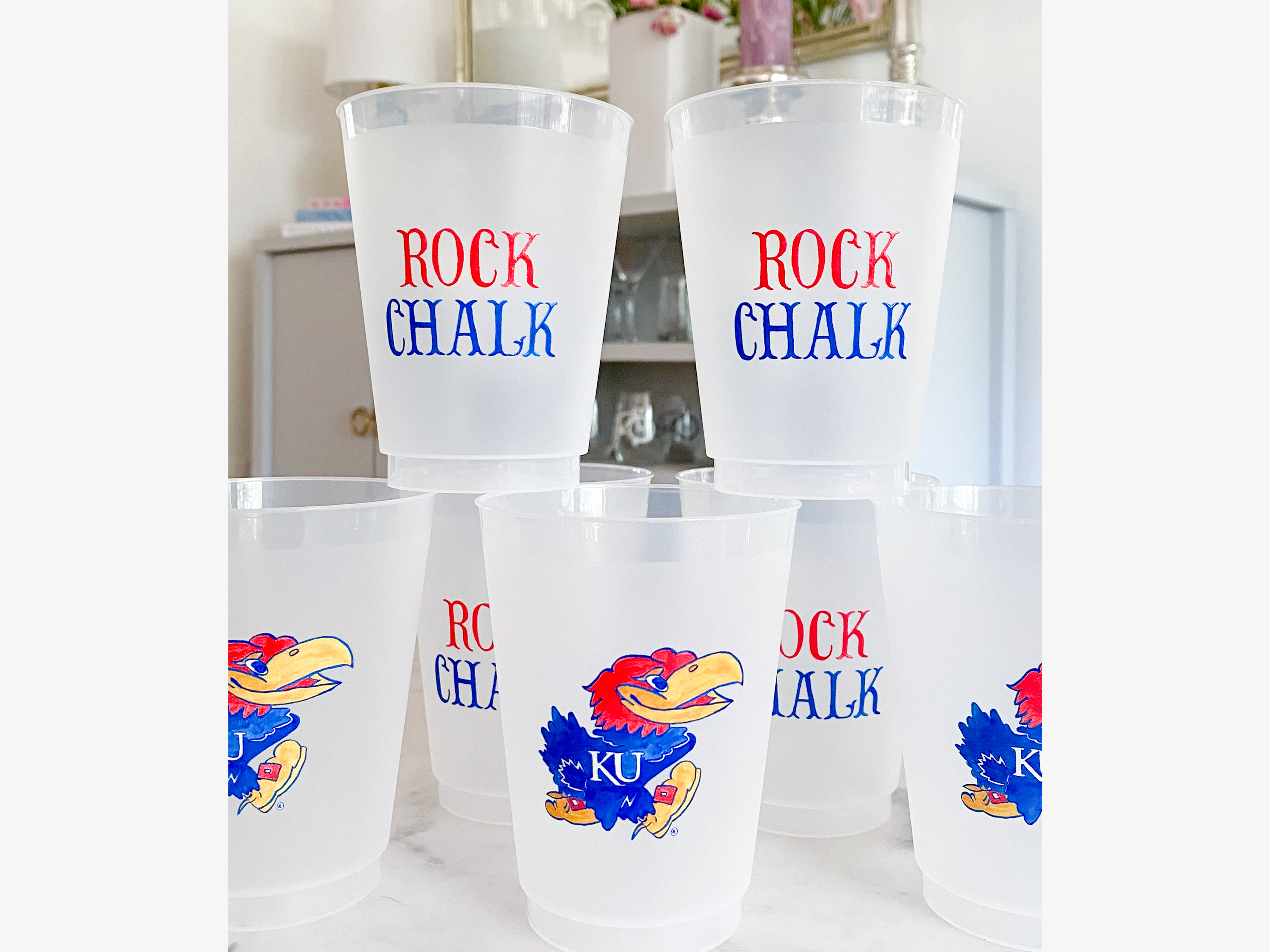 A collection of clear plastic cups with the word "ROCK CHALK" printed on them, featuring a cartoon bird design.