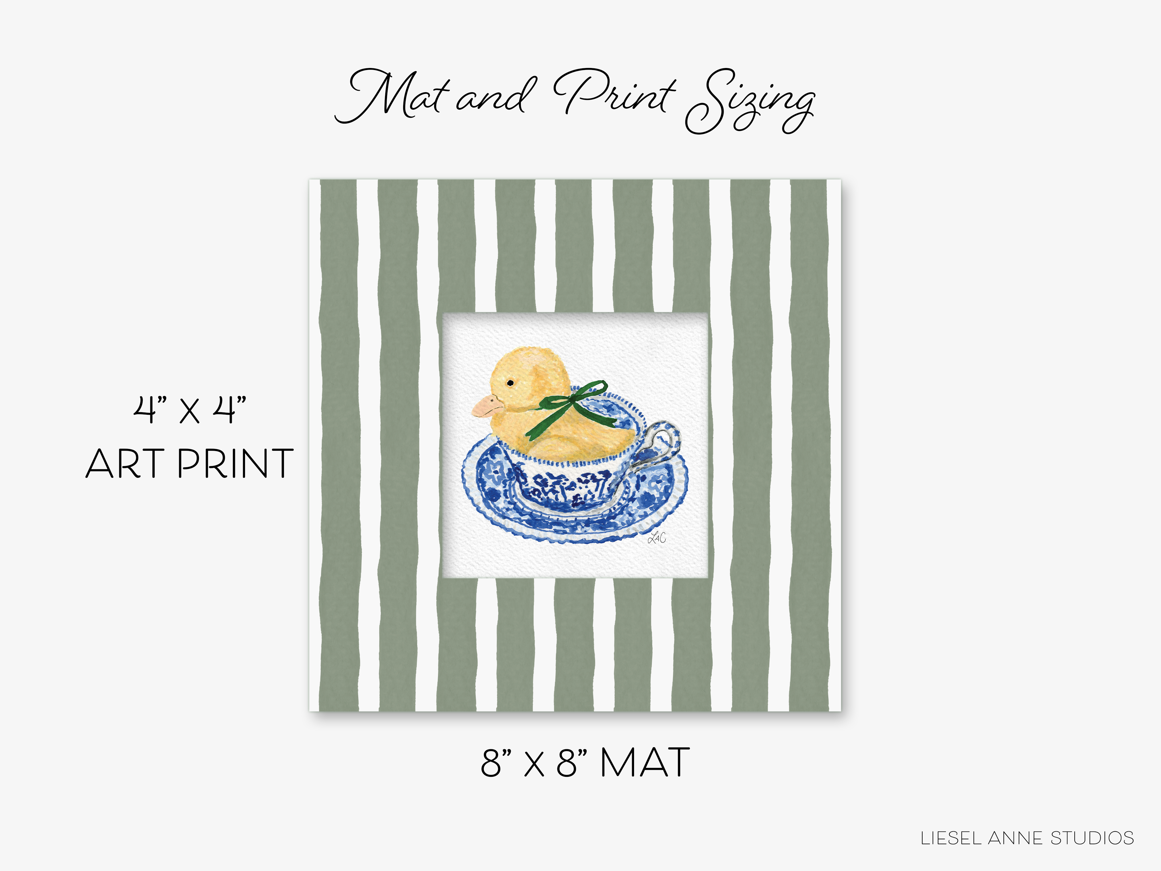 The image is a framed print depicting a yellow duck sitting in a teacup with a green ribbon. The print is a 4" x 4" art print, and it is 8" x 8" in size. The print is from Liesel Anne Studios.