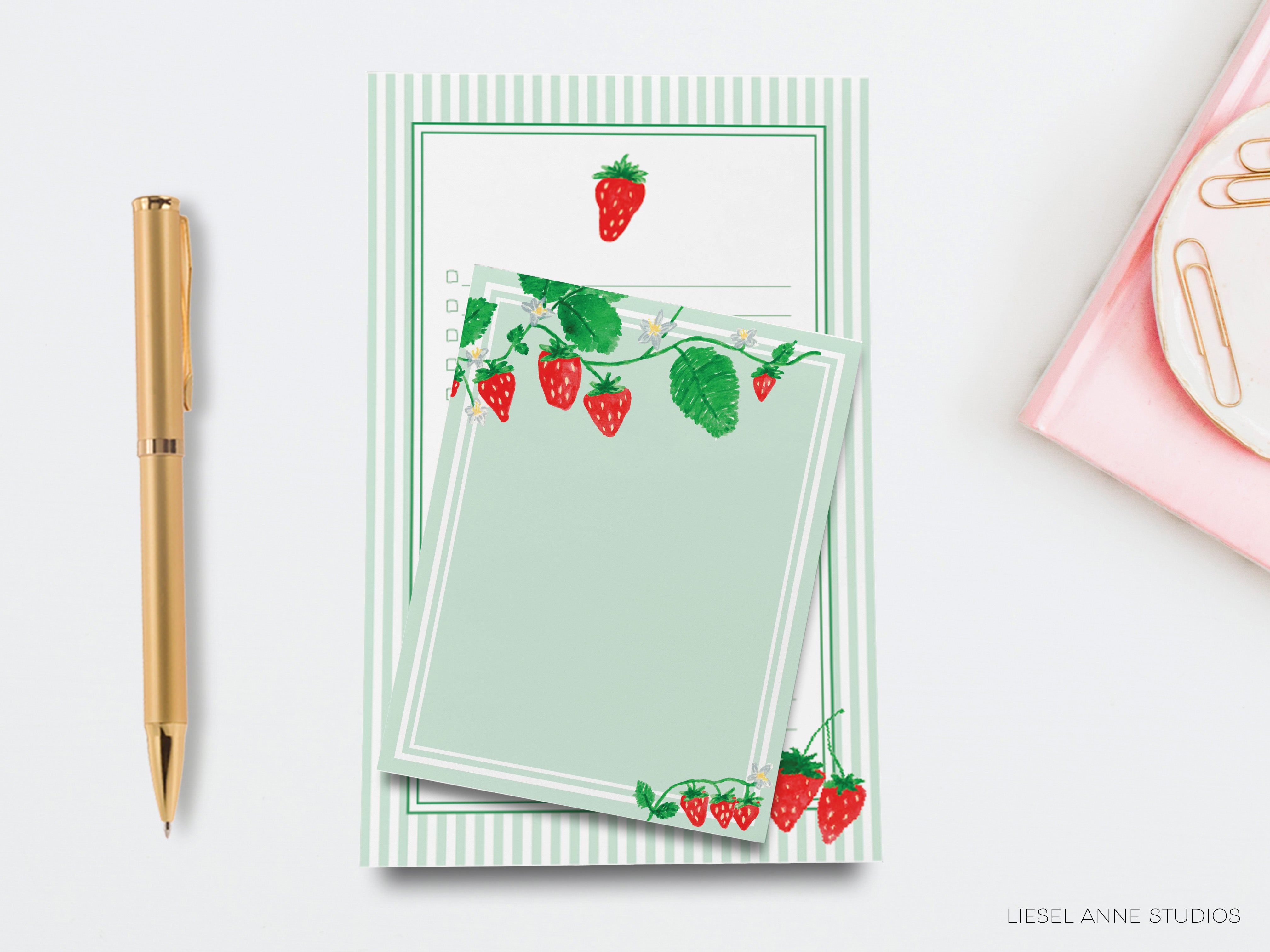 a notepad with strawberries on it next to a pen