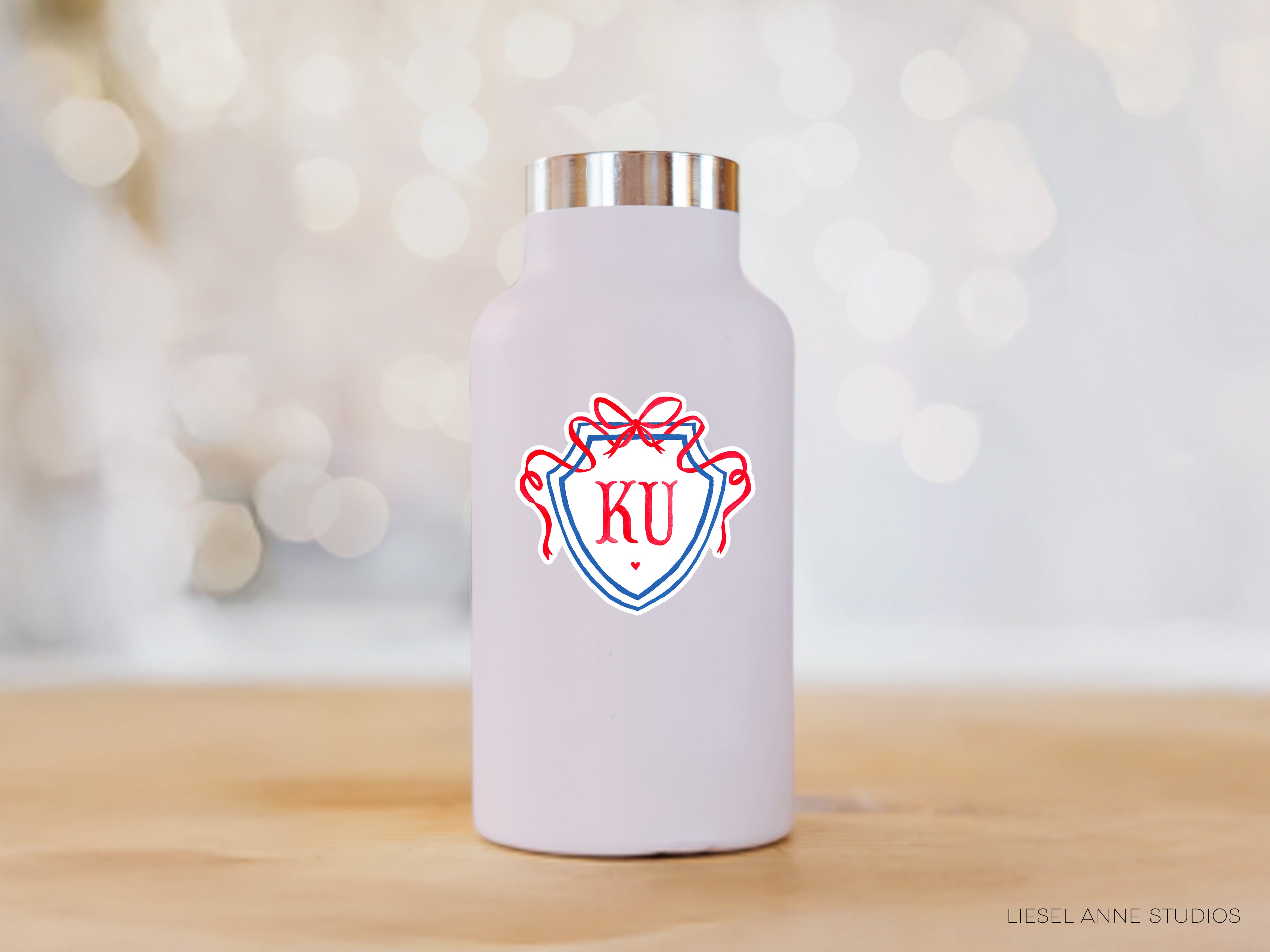 A white water bottle with a red and blue logo on it, placed on a wooden surface against a blurred background.