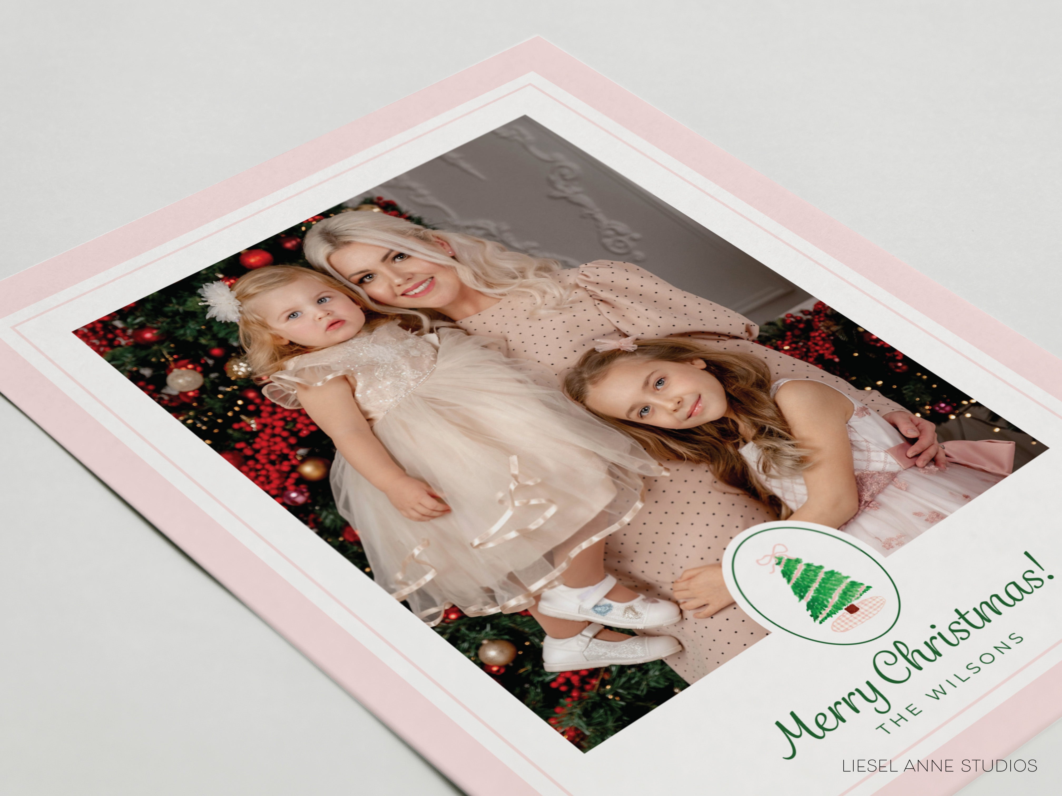 A family portrait of a woman and two young girls, with a Christmas tree in the background.