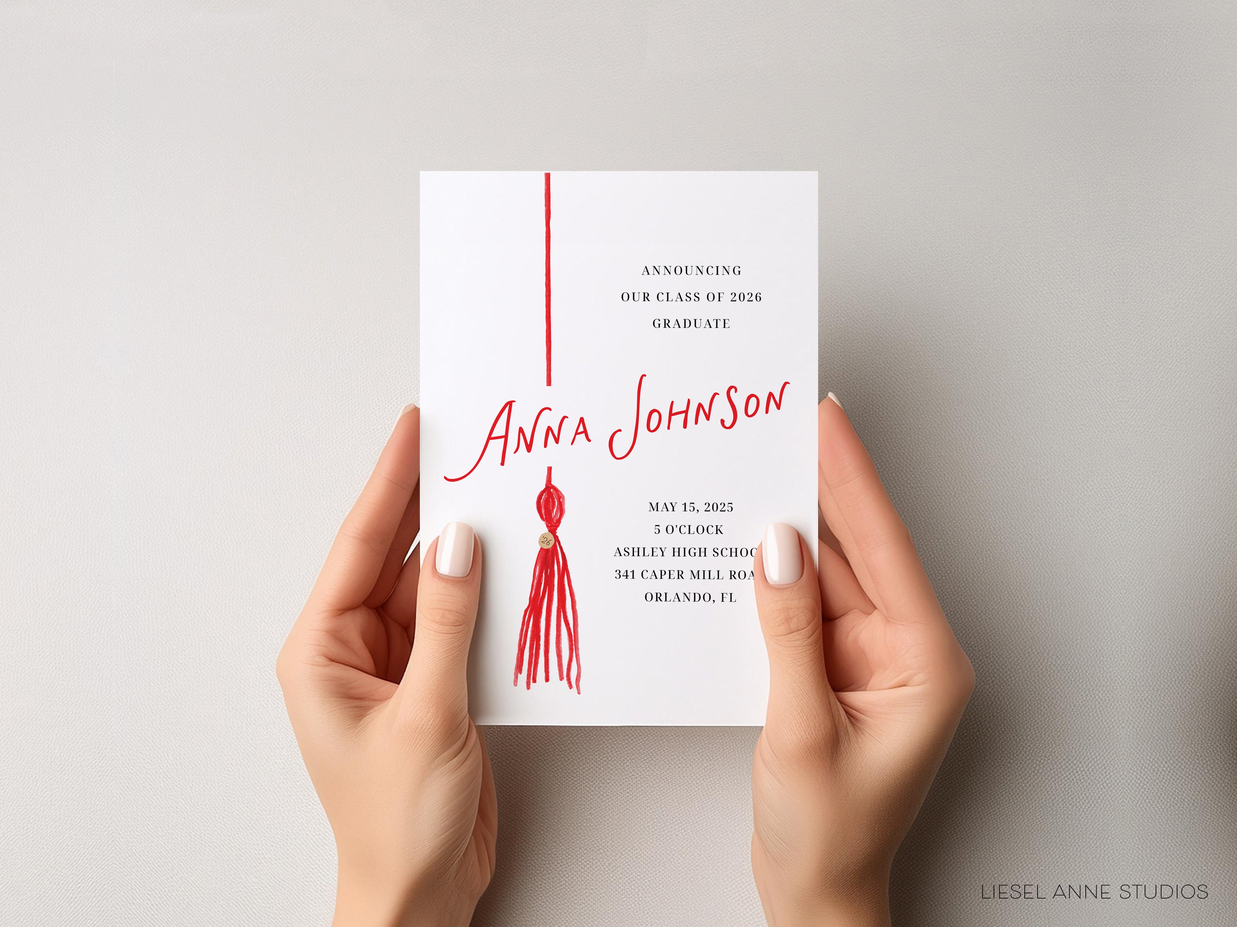 a pair of hands holding a graduation invitation card.