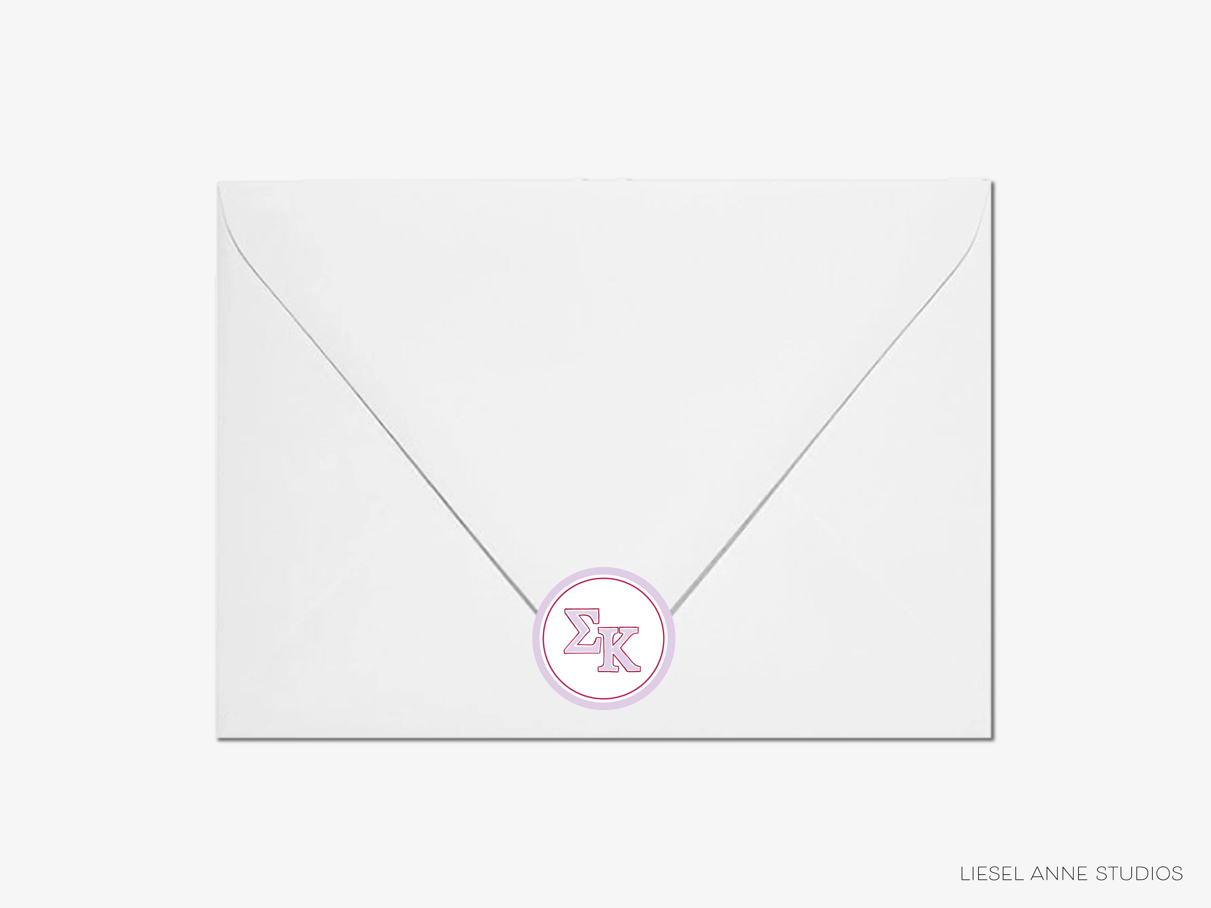 a white envelope with a pink monogrammed letter k on it