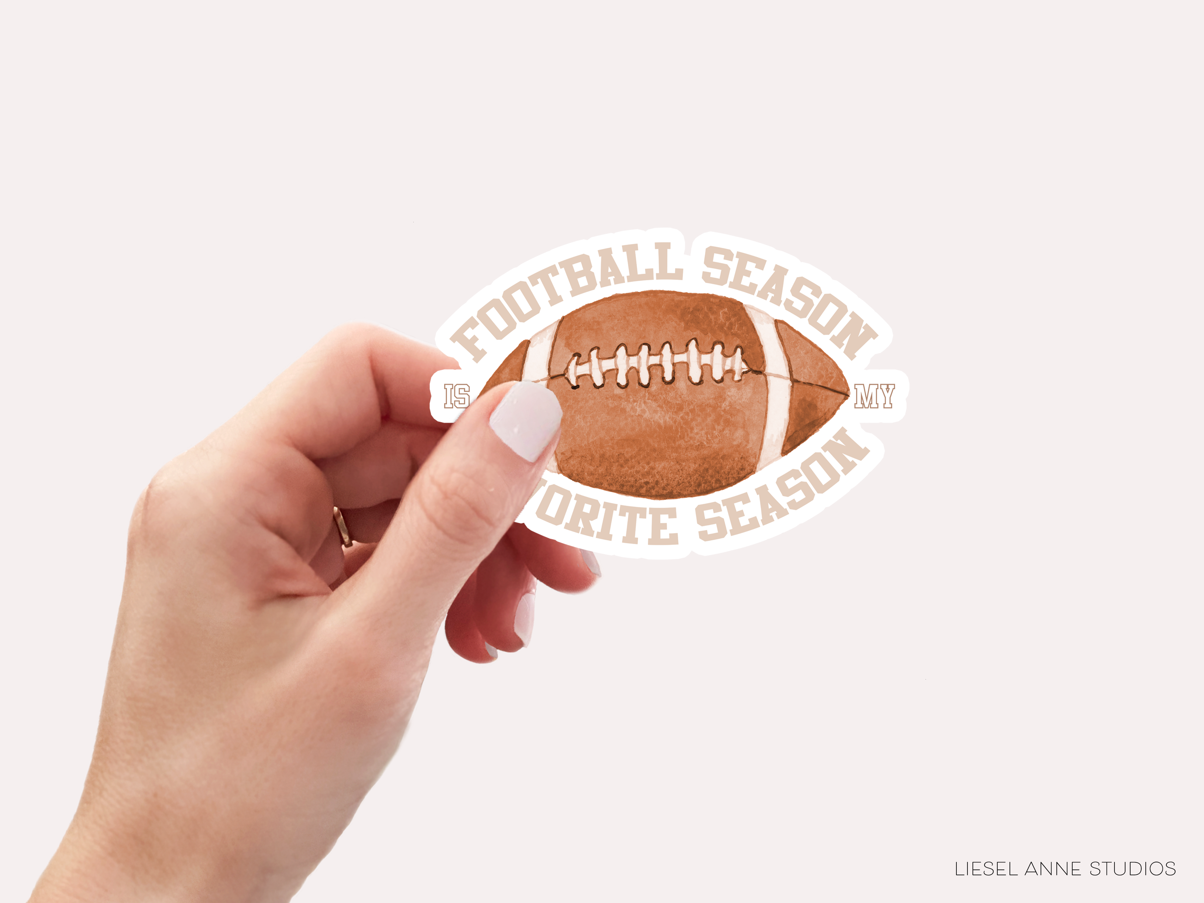 A hand holding a sticker with a football and the text "FOOTBALL SEASON" and "MY" printed on it.