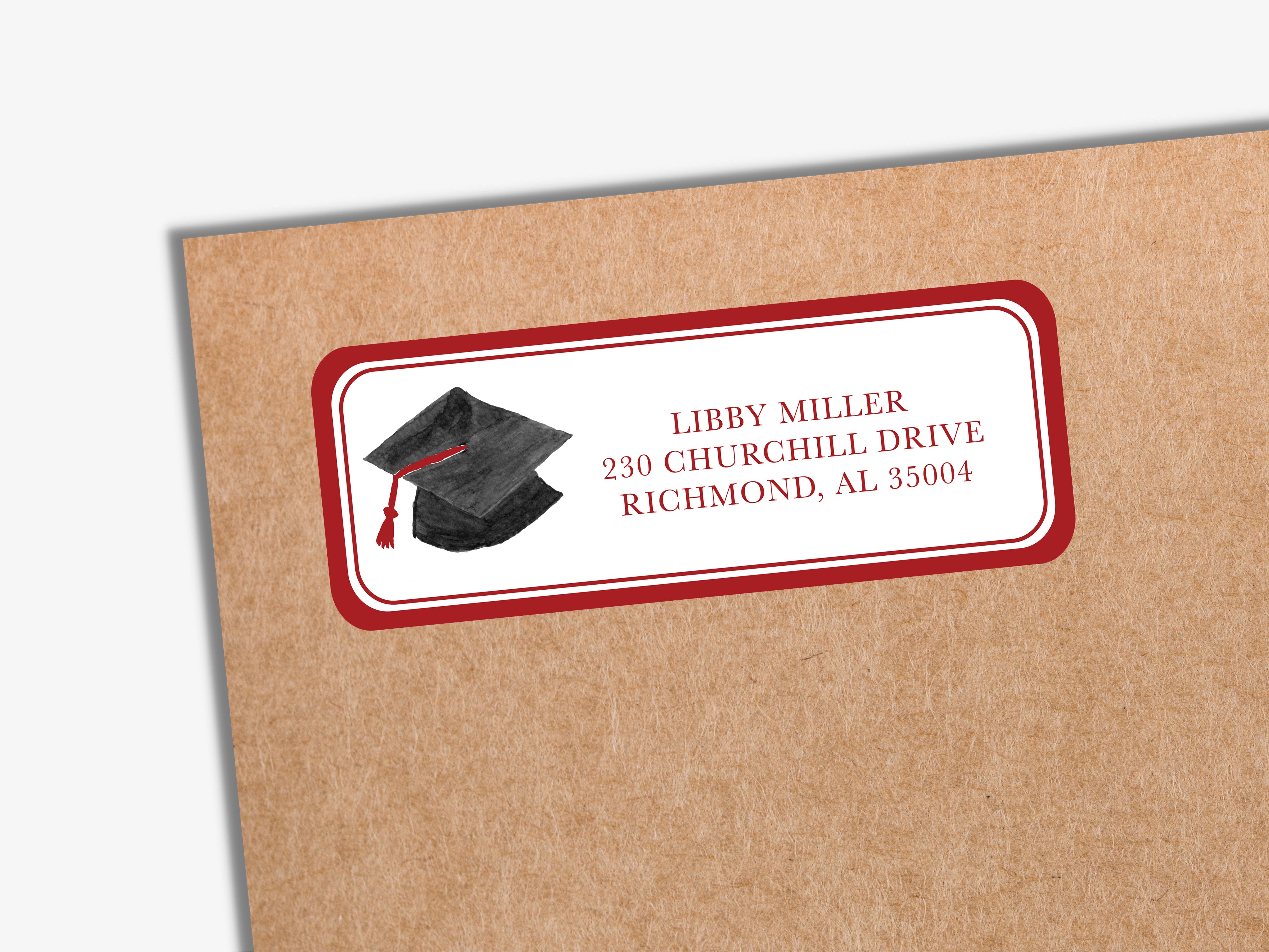 A brown envelope with a red and white label that reads "LIBBY MILLER 230 CHURCHILL DRIVE RICHMOND, AL 35004" and features an illustration of a graduation cap.