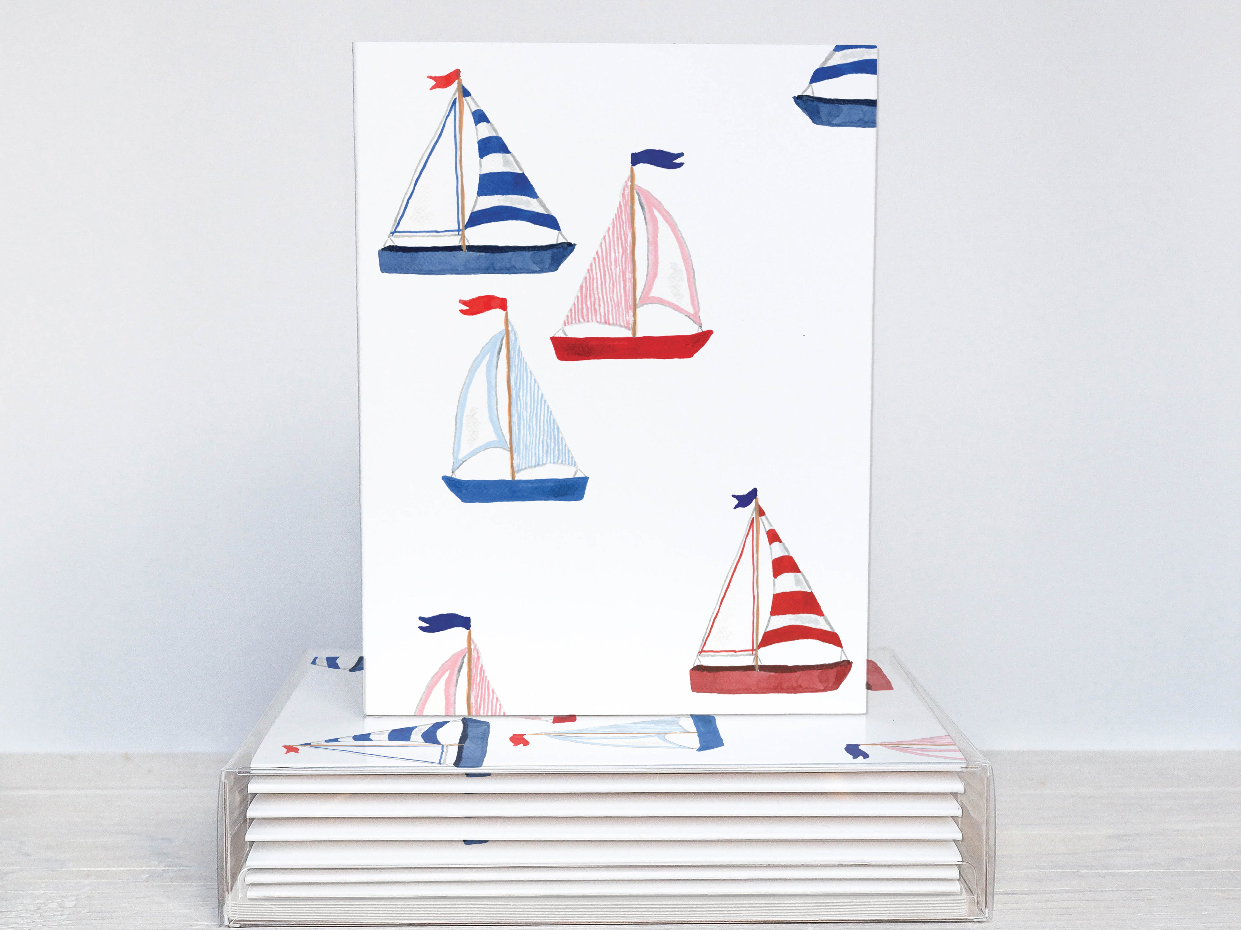 A white card with a repeating pattern of sailboats in blue, red, and white colors.